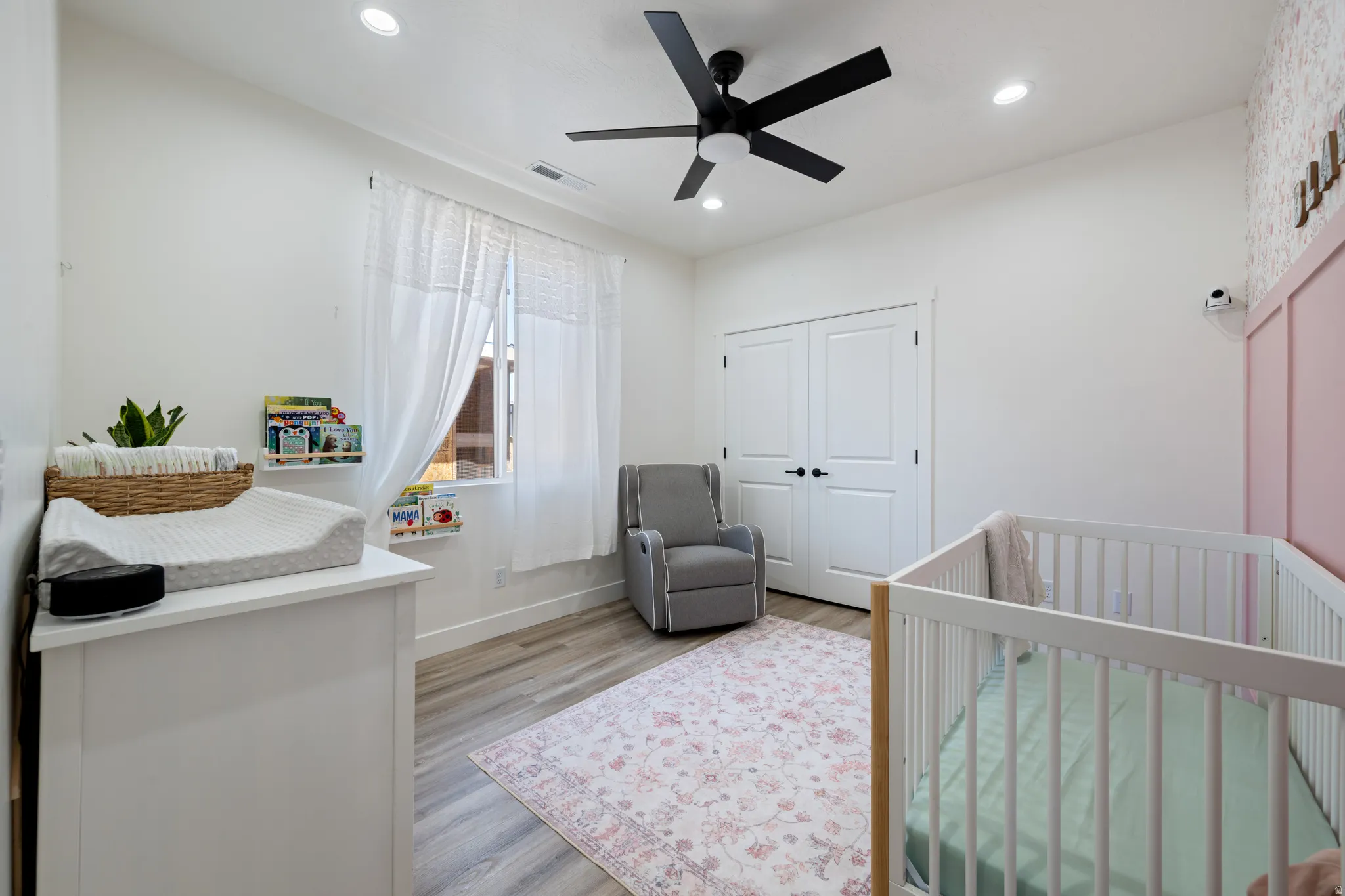 Bedroom featuring a nursery area, light wood-type flooring, ceiling fan, recessed lighting, and a closet