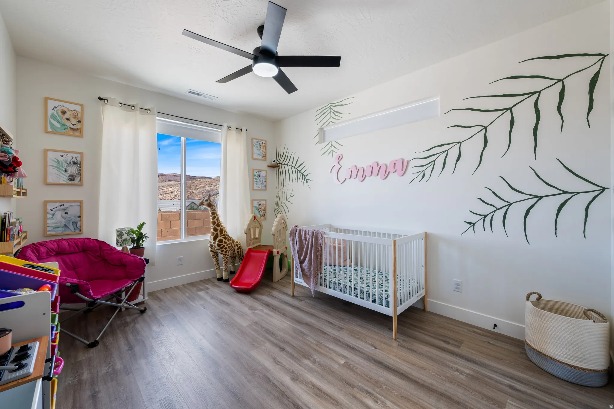 Bedroom featuring wood finished floors, a crib, and a ceiling fan