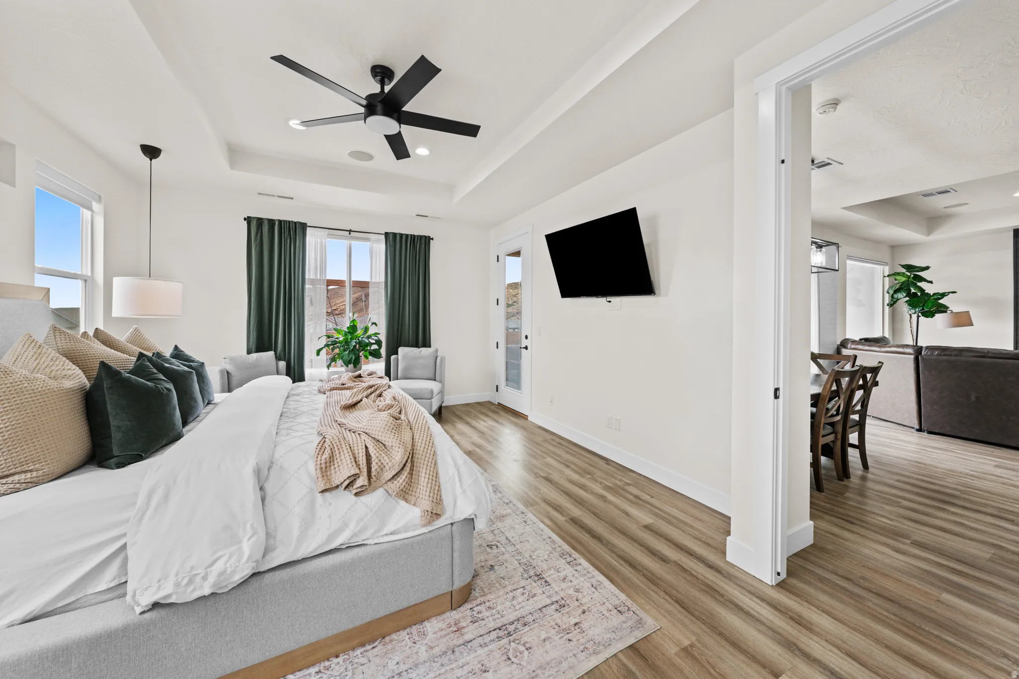 Bedroom with a tray ceiling, light wood-type flooring, ceiling fan, and access to outside