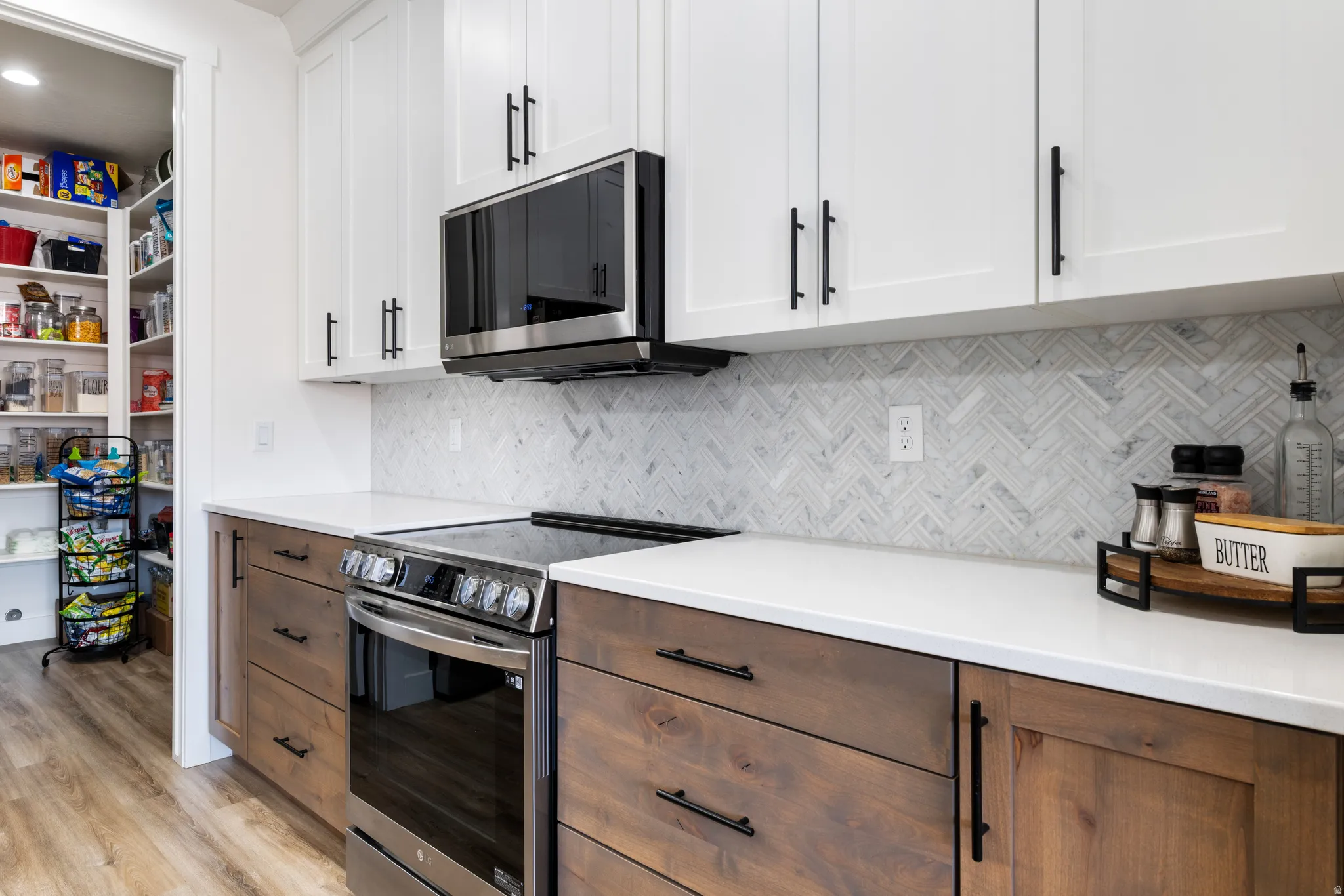 Kitchen with two tone cabinets, stainless steel appliances, backsplash, and light wood-style floors