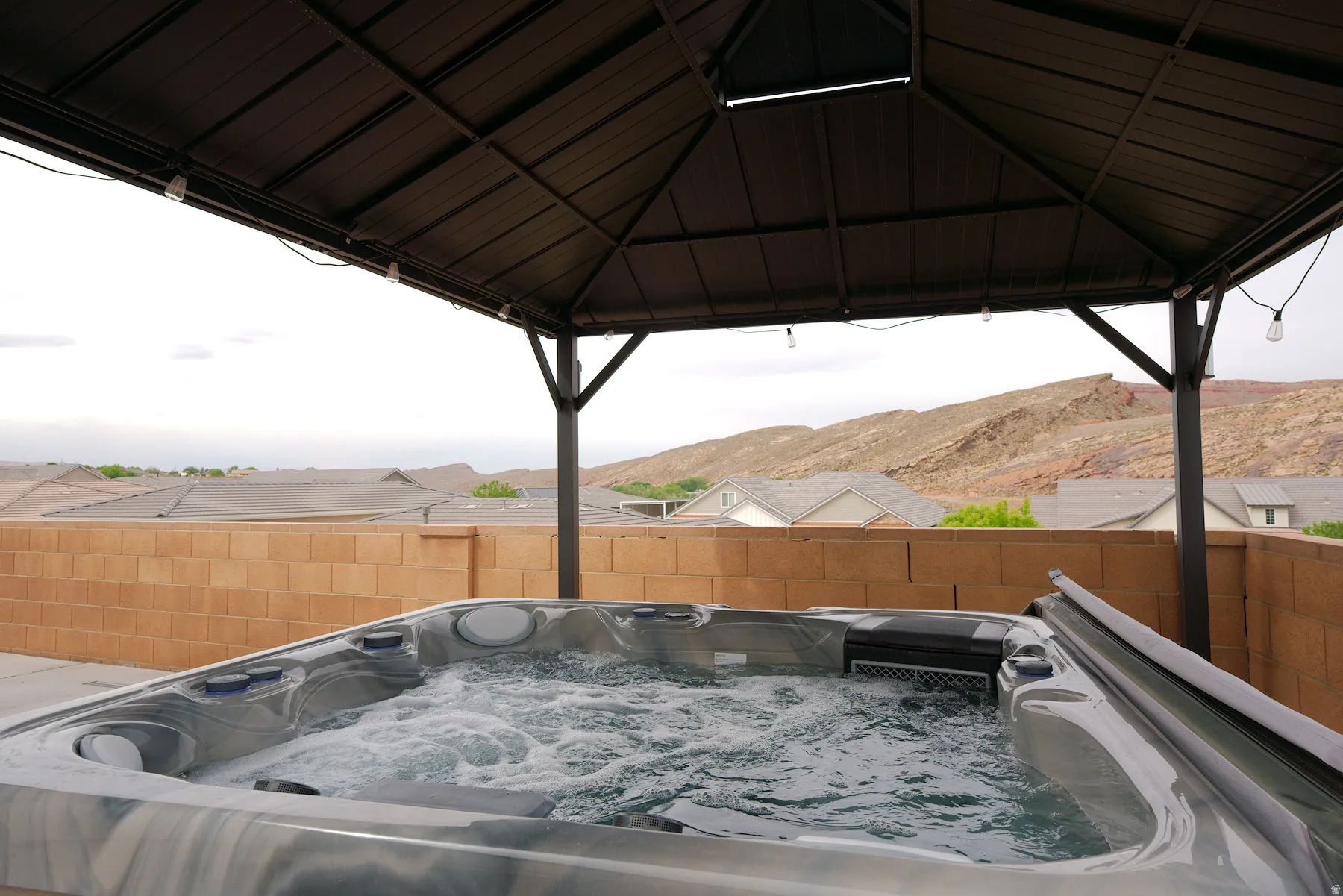 Fenced backyard featuring a gazebo, a mountain view, and a hot tub