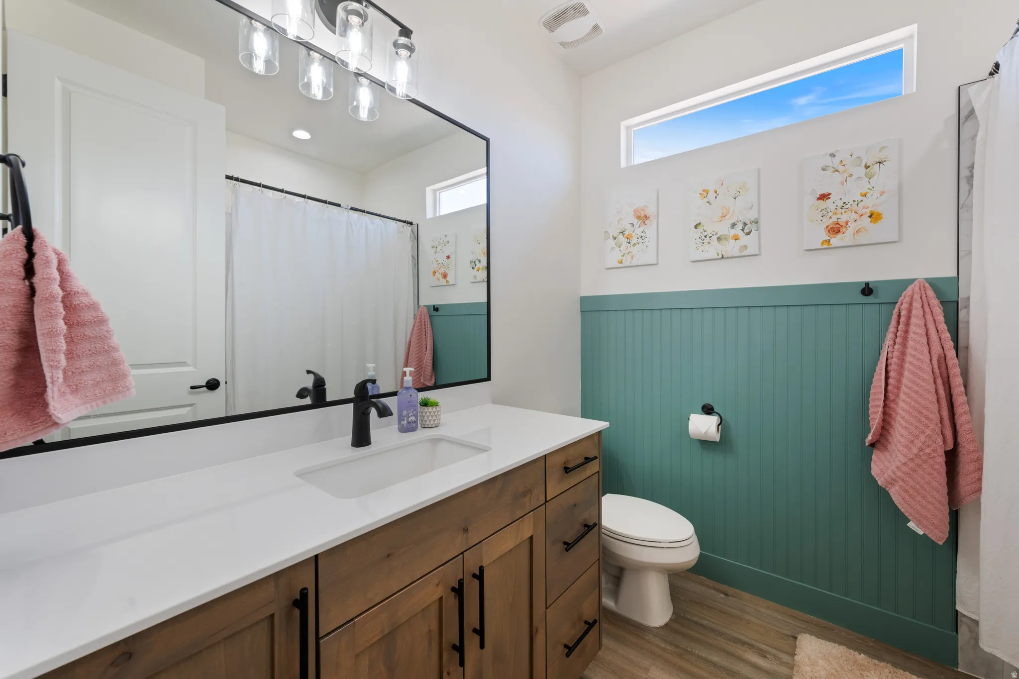 Bathroom featuring vanity, light wood-type flooring, curtained shower, and a wainscoted wall