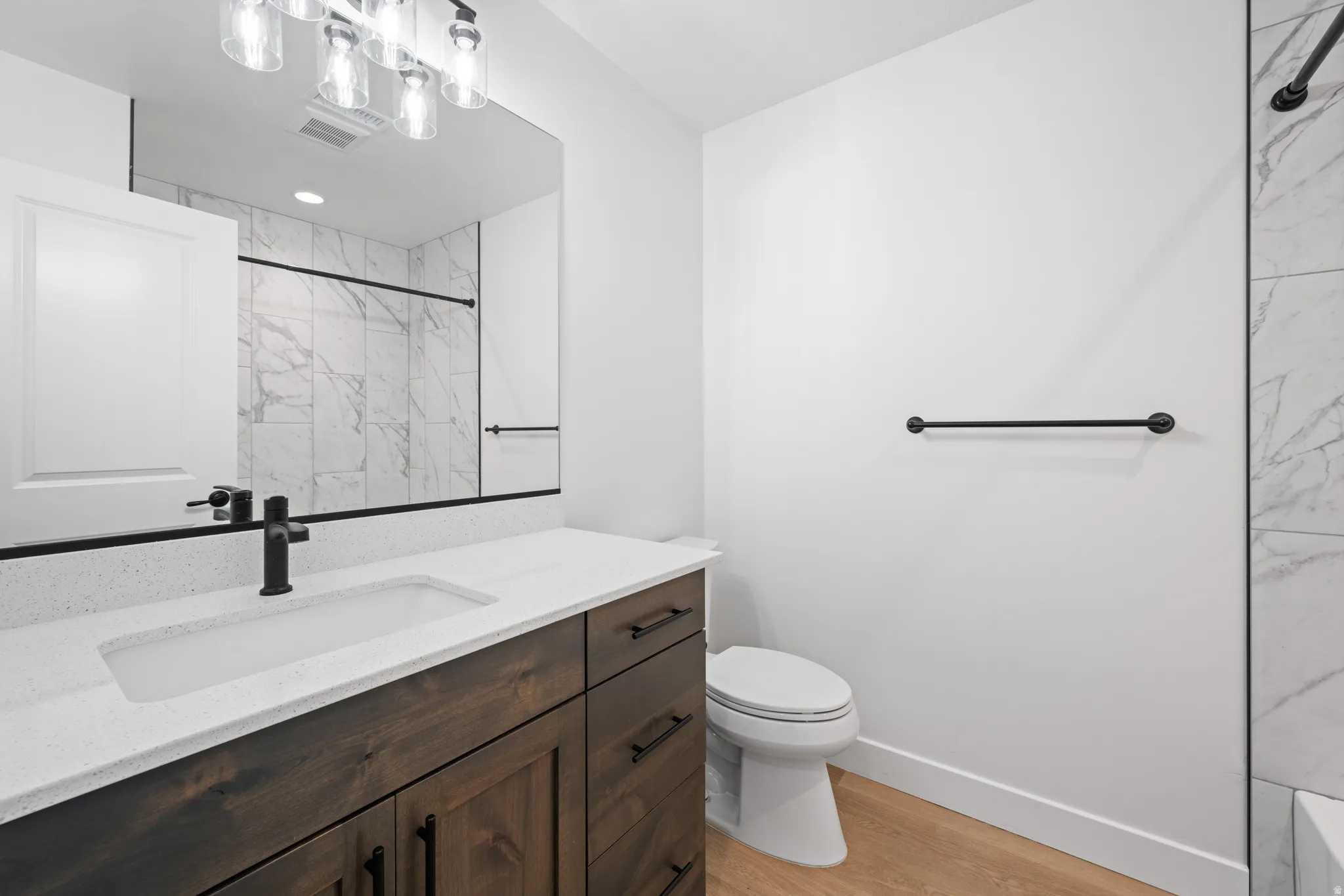 Full bathroom featuring vanity, a marble finish shower, and light wood-style flooring