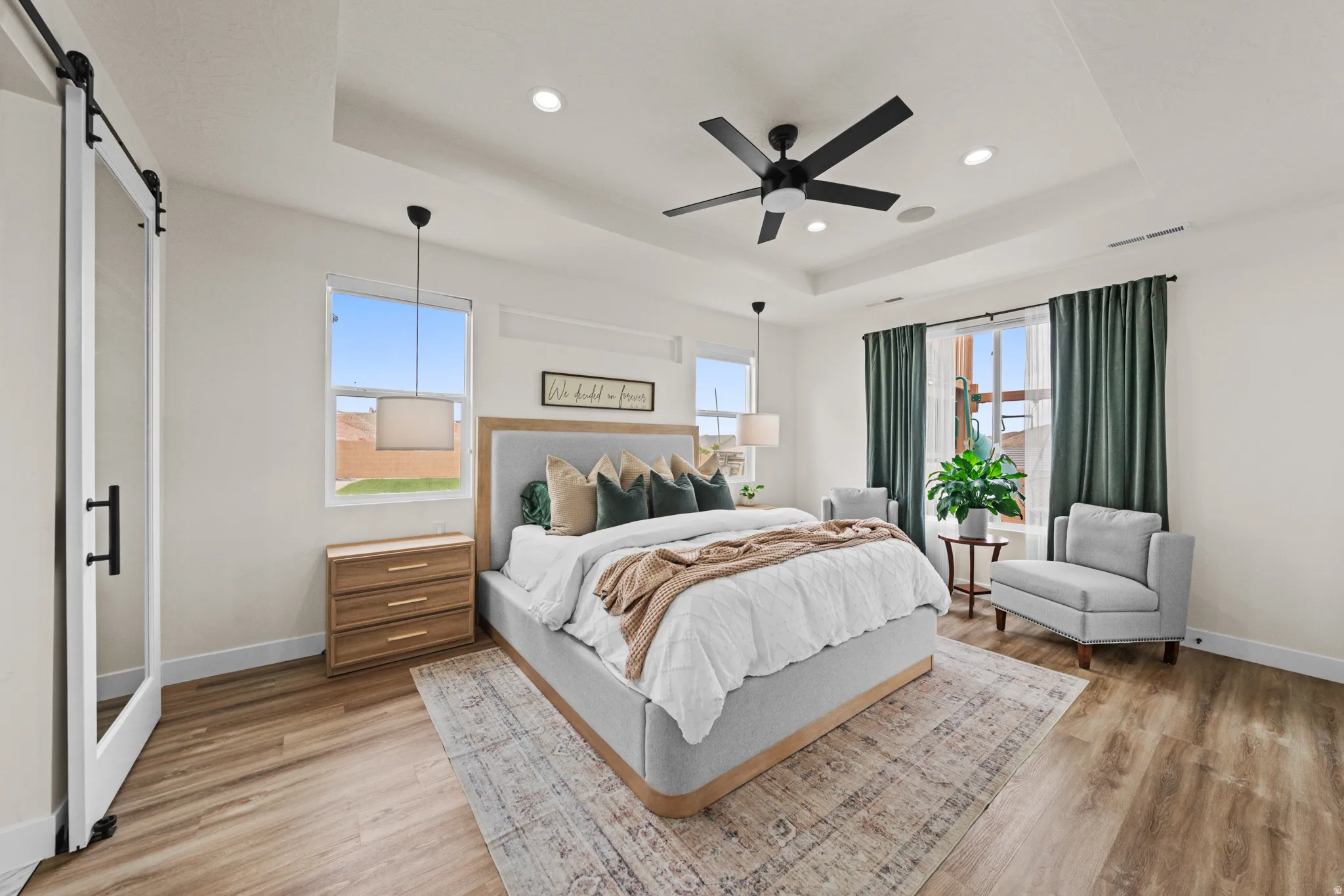 Bedroom featuring a barn door, light wood-style flooring, ceiling fan, multiple windows, and recessed lighting