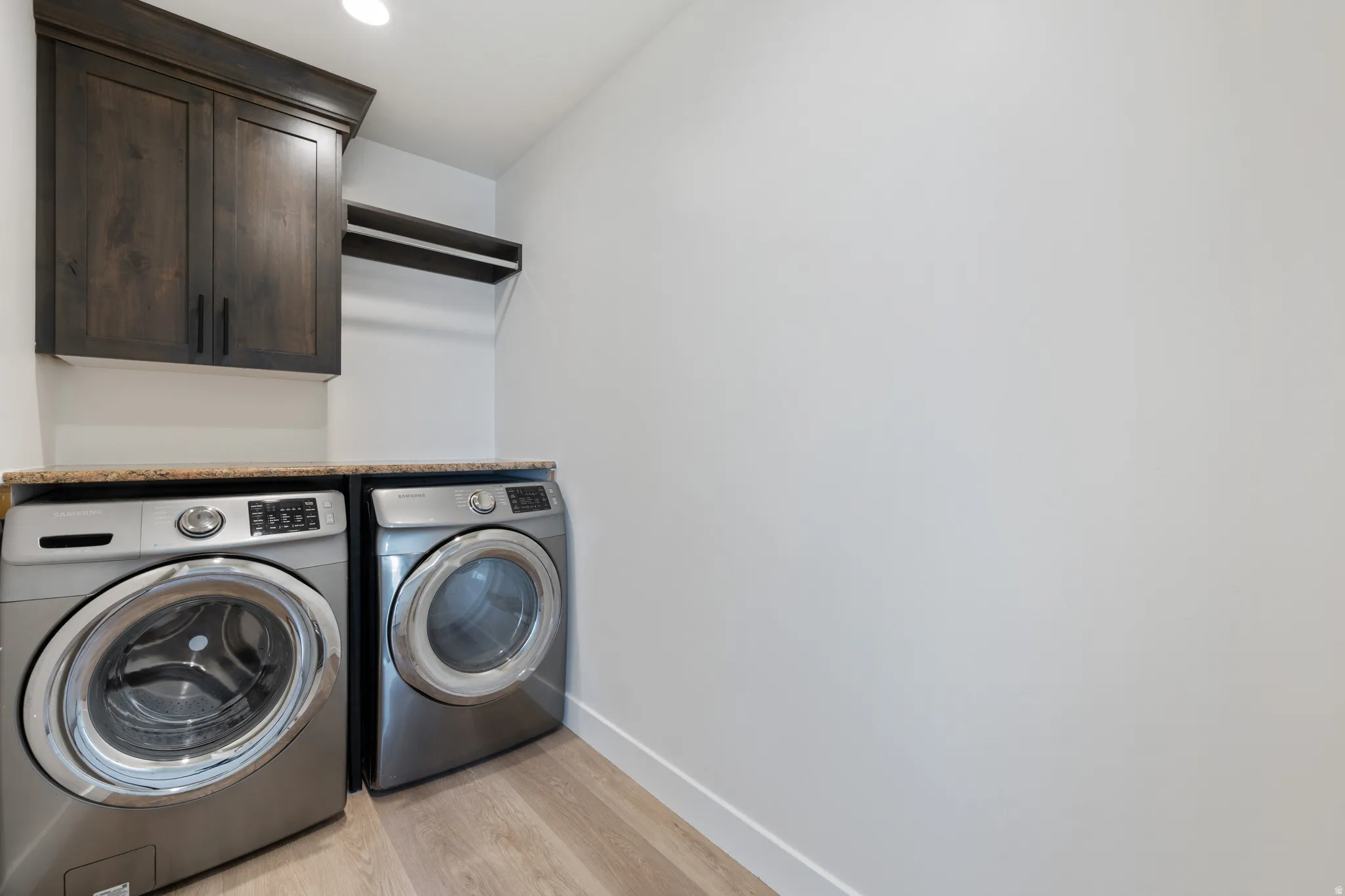 Laundry room featuring light wood-type flooring, independent washer and dryer, and cabinet space