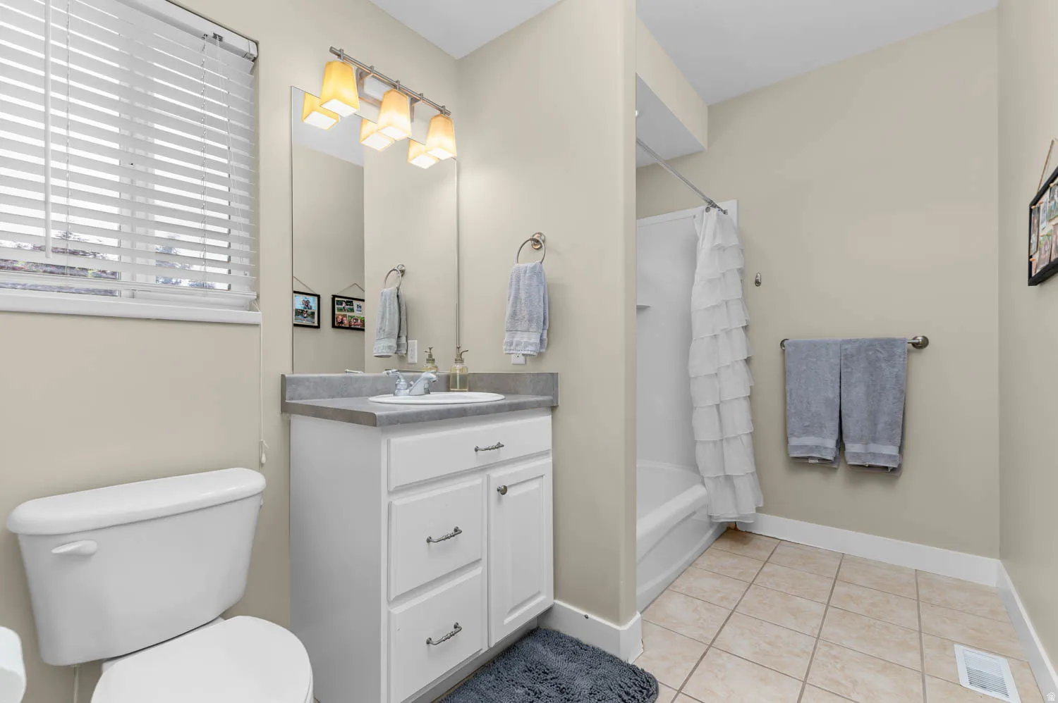 Bathroom featuring vanity, shower / bath combo with shower curtain, and light tile patterned floors