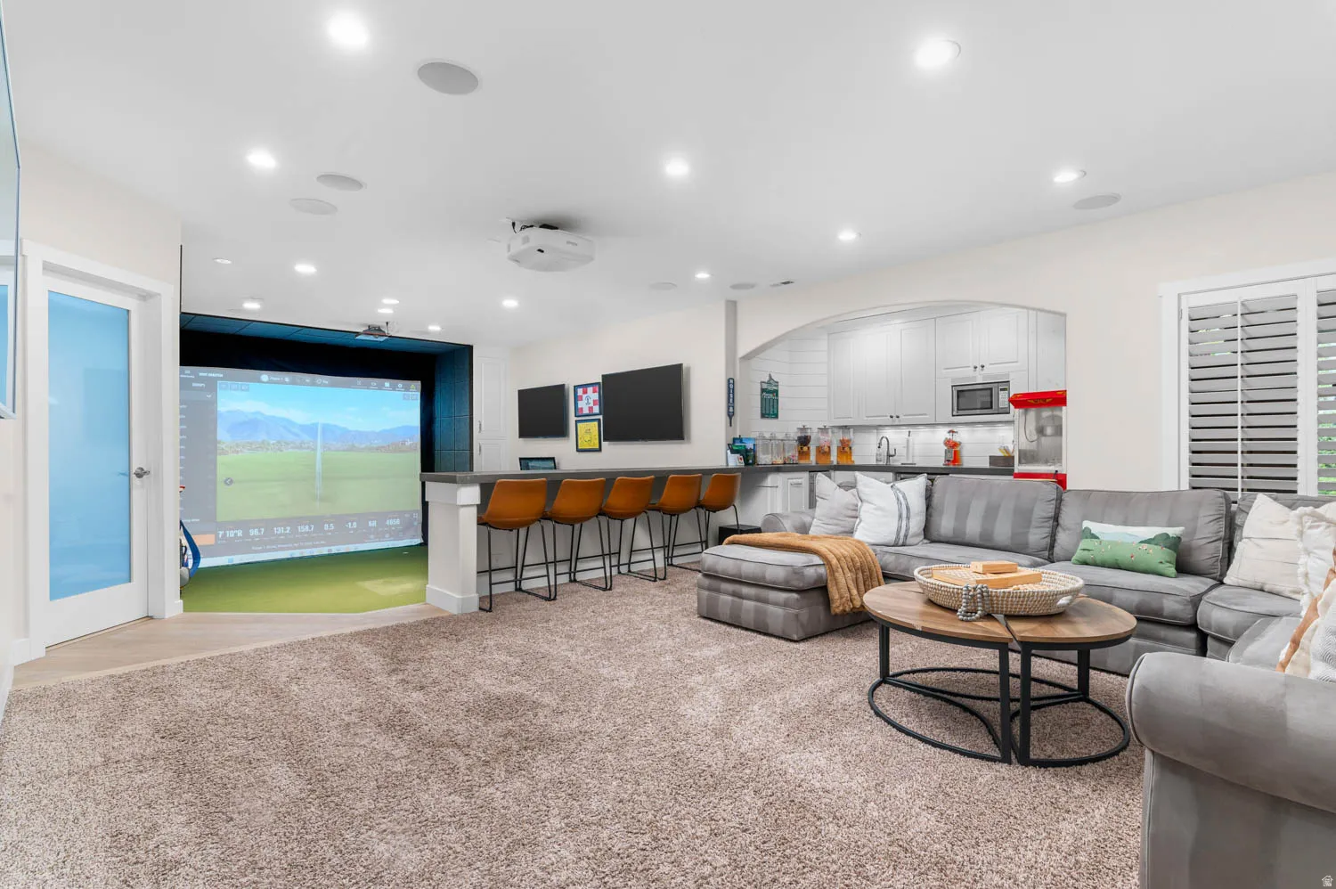 Living area with golf simulator, light carpet, and recessed lighting