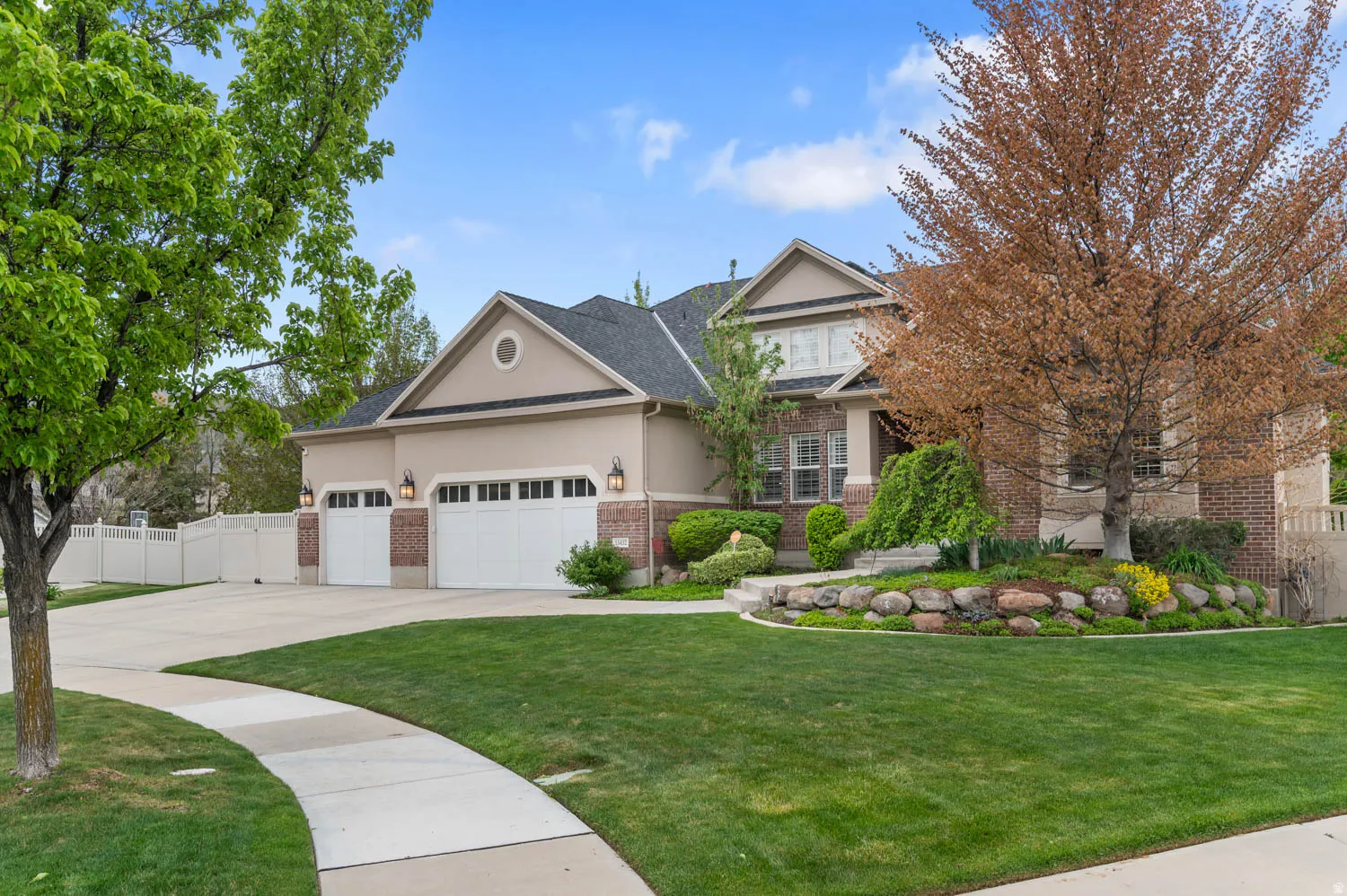 View of front of home featuring brick siding, stucco siding, concrete driveway, and an attached garage