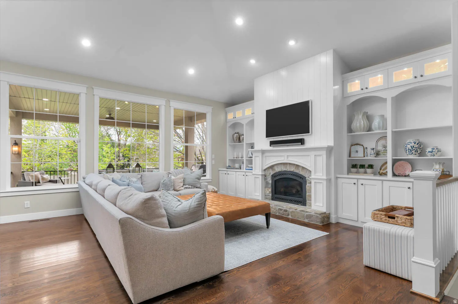 Living area featuring a stone fireplace, dark wood-style floors, recessed lighting, and built in features