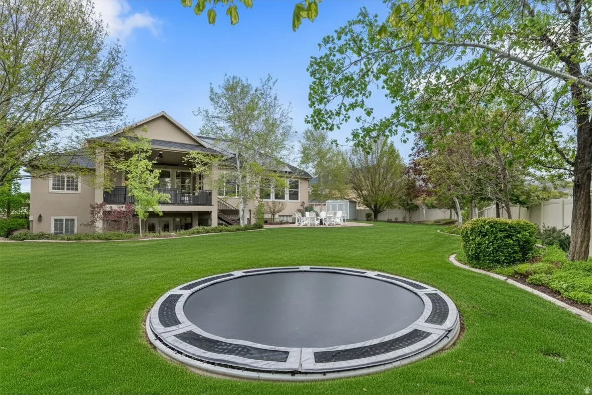 Fenced yard featuring a built-in trampoline and a storage unit