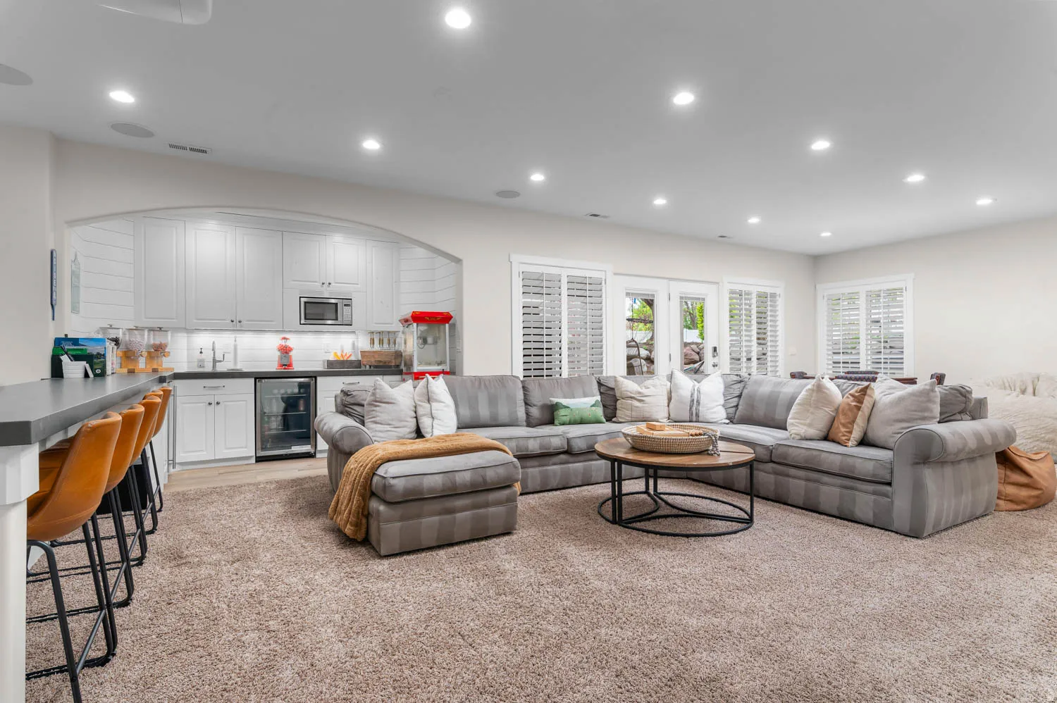 Living room featuring recessed lighting, light carpet, wet bar, beverage cooler, and arched walkways