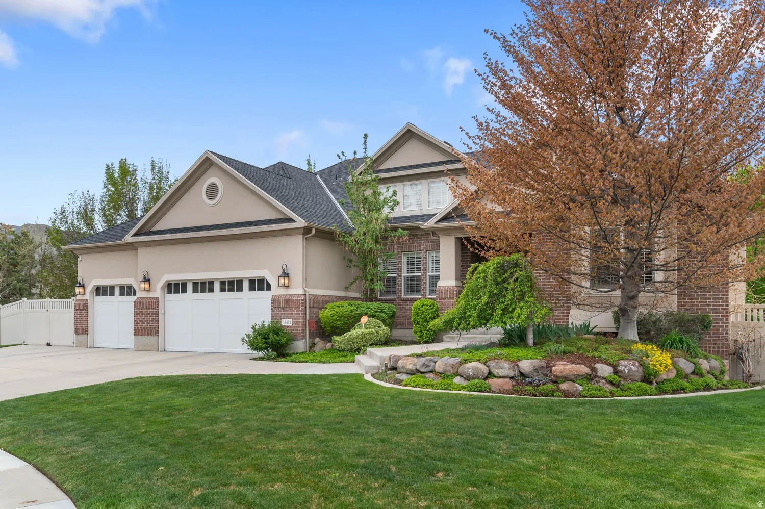 View of front facade featuring brick siding, stucco siding, an attached garage, and driveway