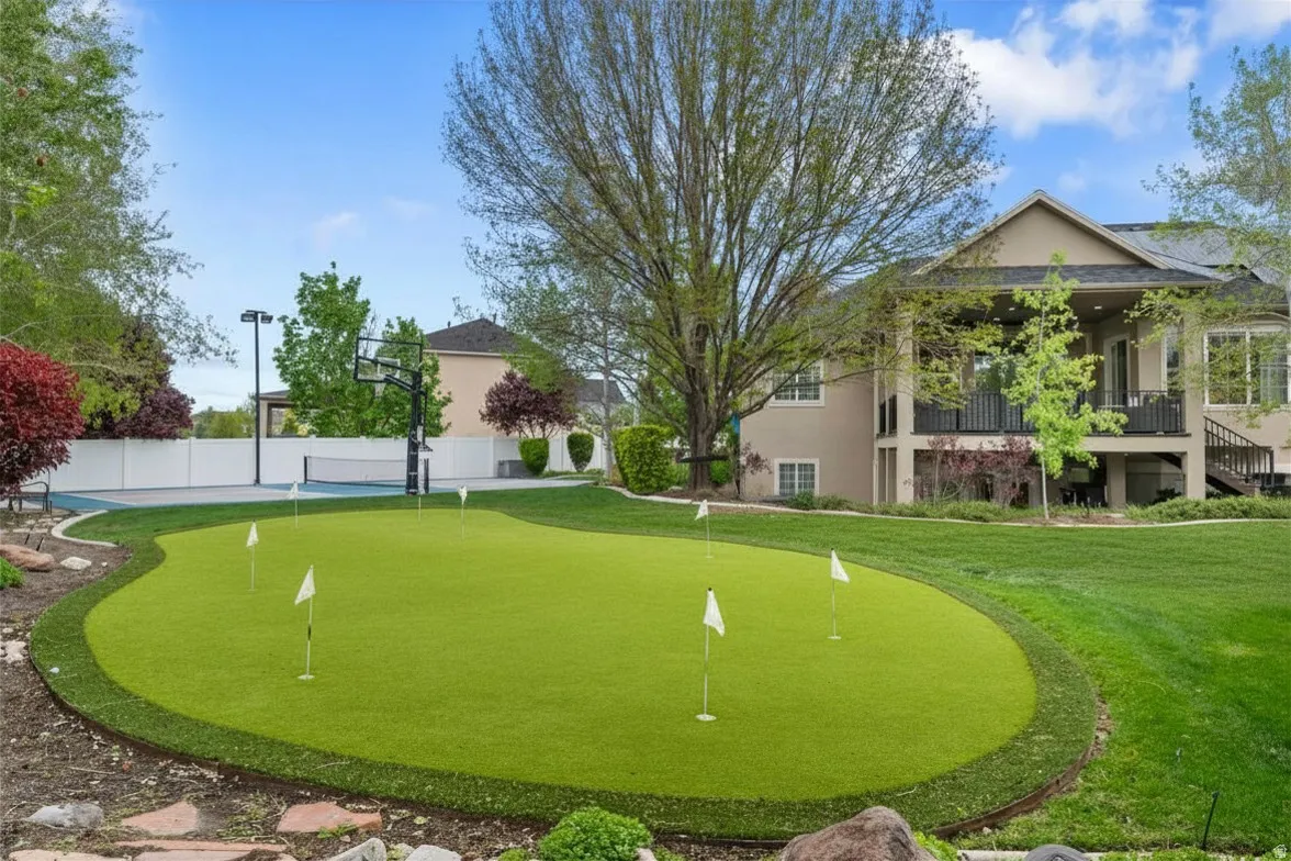 Fenced backyard with a putting area and a balcony