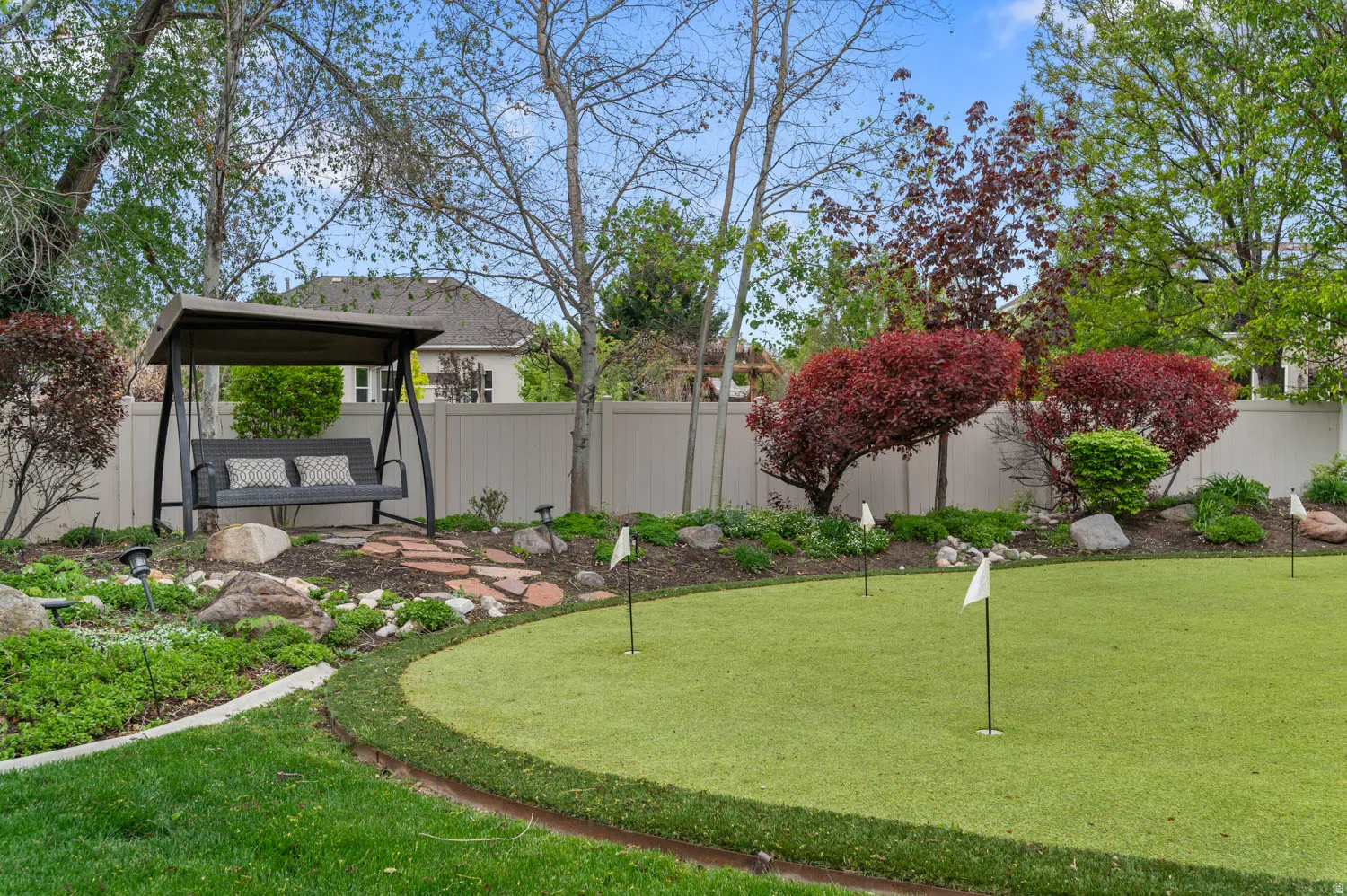 Fenced backyard with a putting area