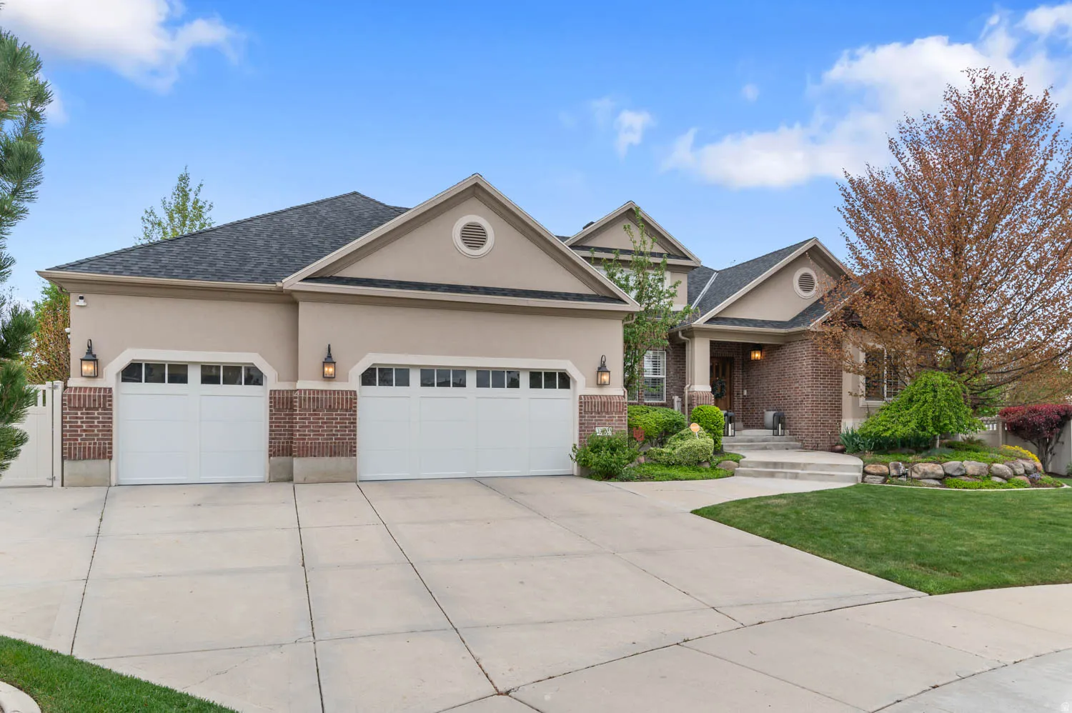 View of front of home featuring a garage, brick siding, driveway, and stucco siding
