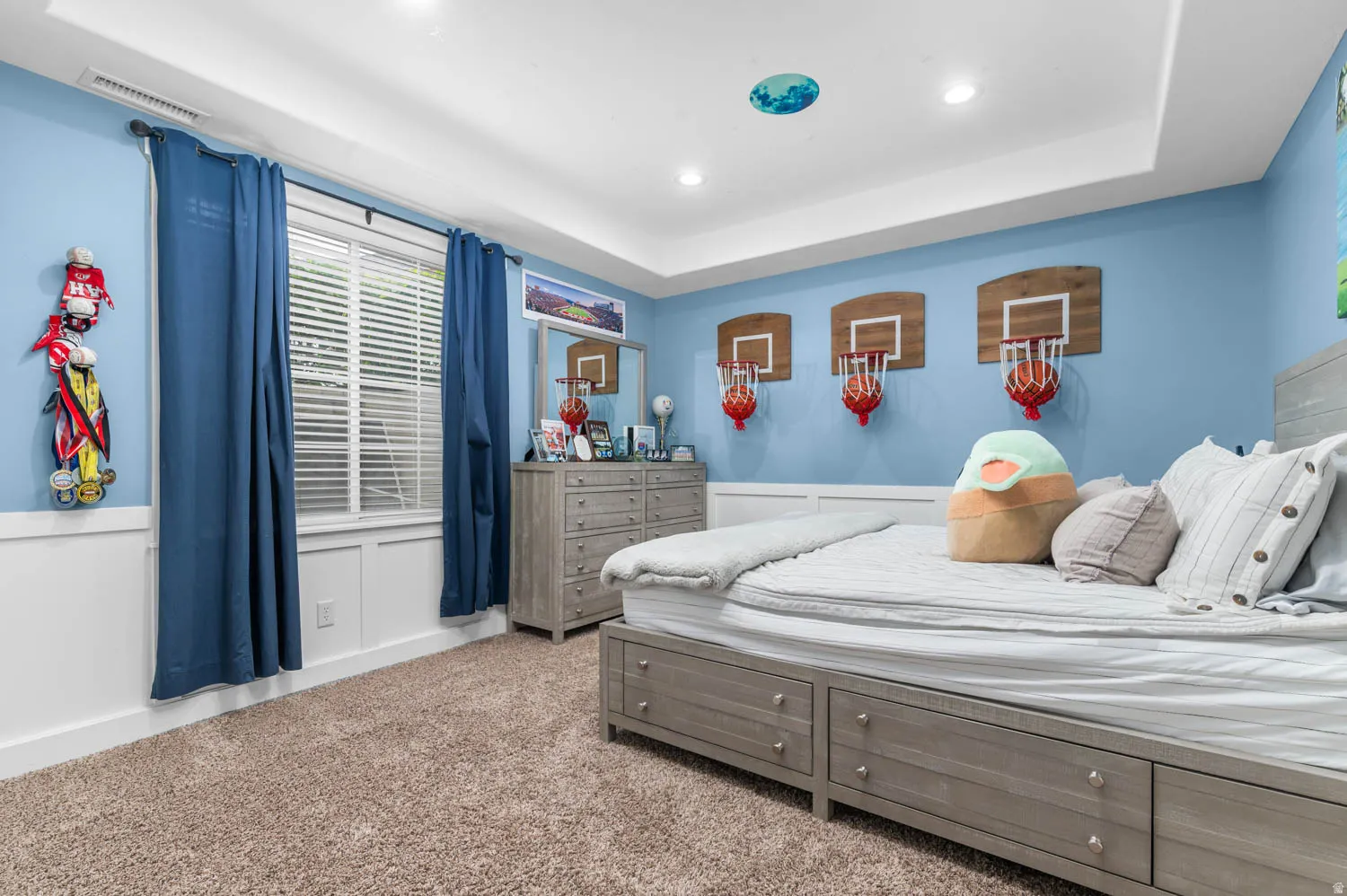 Bedroom featuring a tray ceiling, light carpet, recessed lighting, and wainscoting