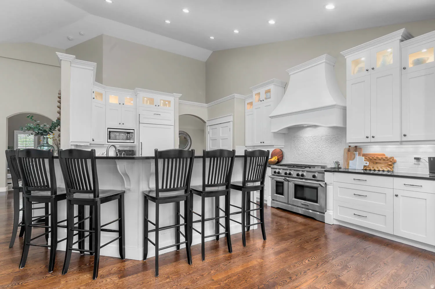 Kitchen with glass fronted cabinets, a breakfast bar area, backsplash, stainless steel appliances, and lofted ceiling