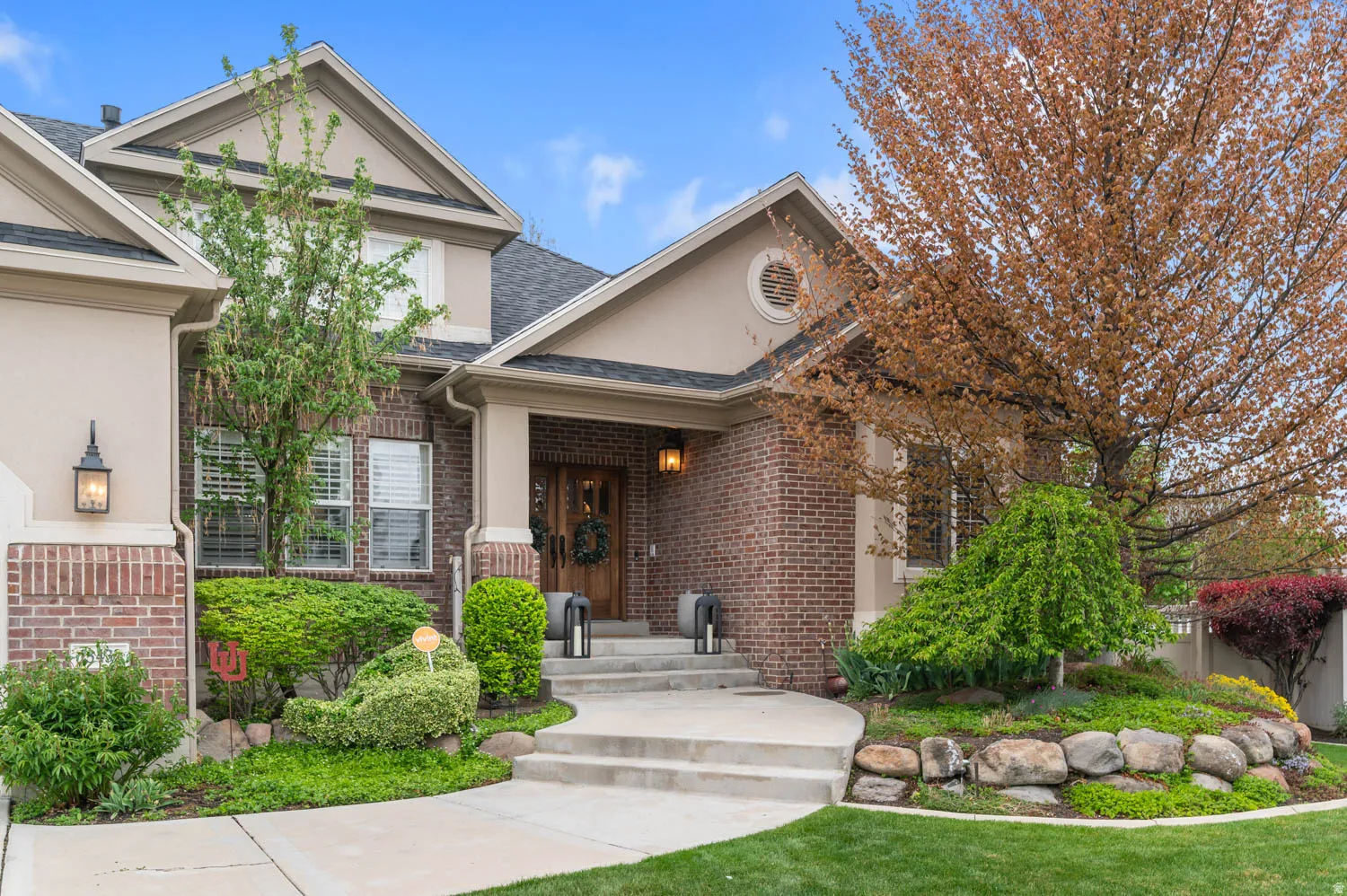 View of front of home with brick siding, stucco siding, and a shingled roof