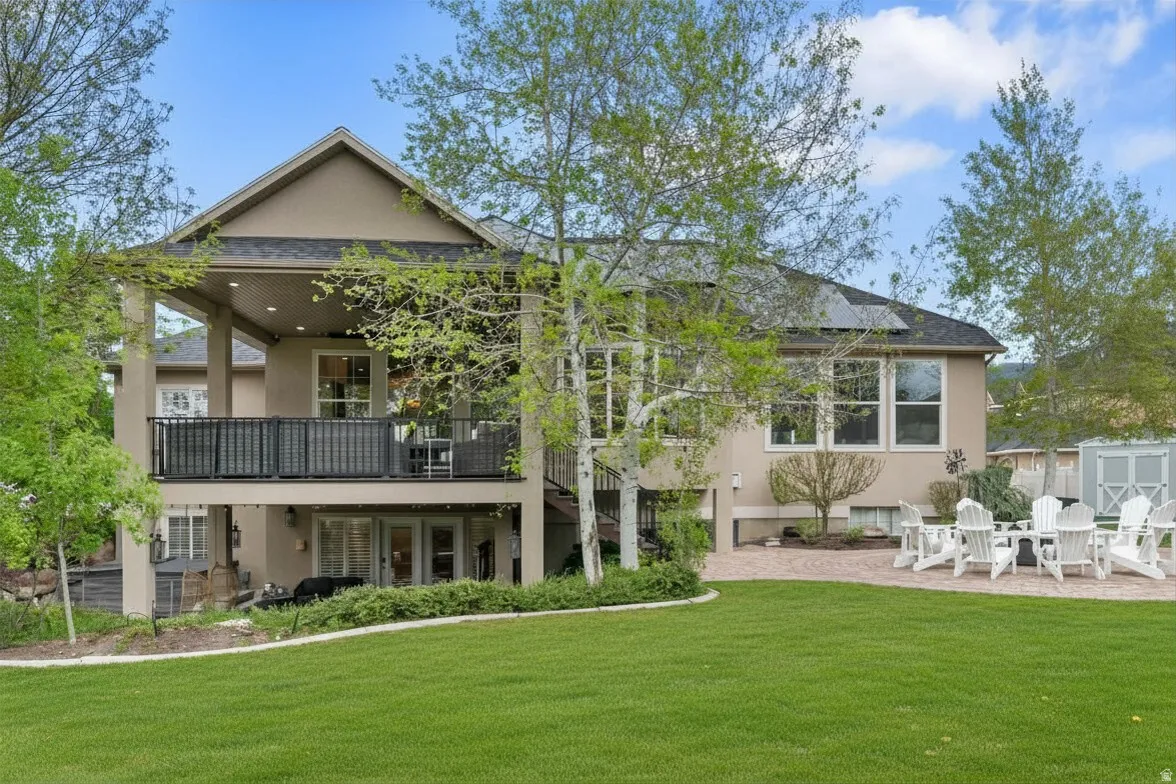 Rear view of property with stucco siding, a yard, a shed, and a patio area