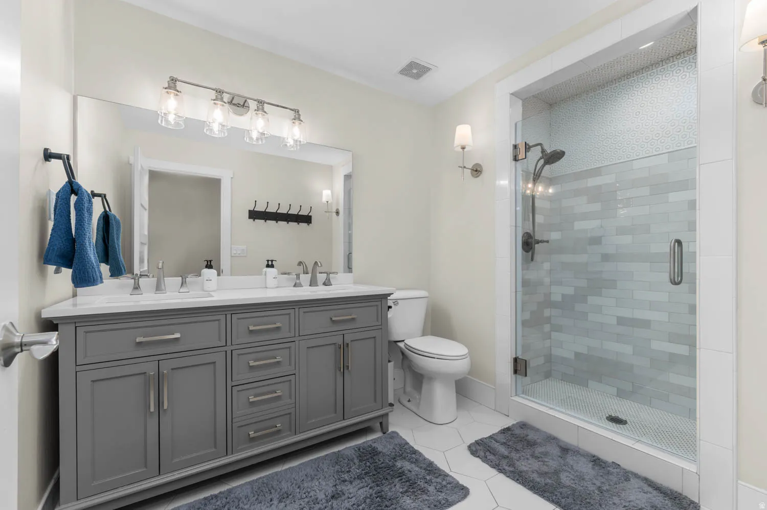 Bathroom featuring double vanity, a stall shower, and light tile patterned flooring