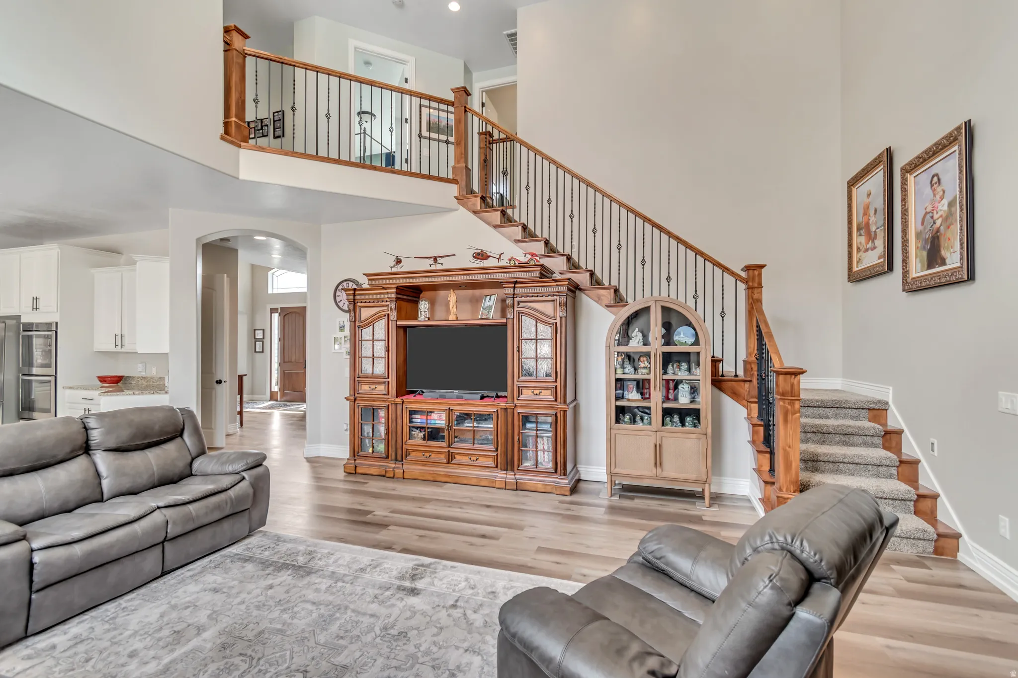 Living area featuring arched walkways, light wood-style floors, and a high ceiling