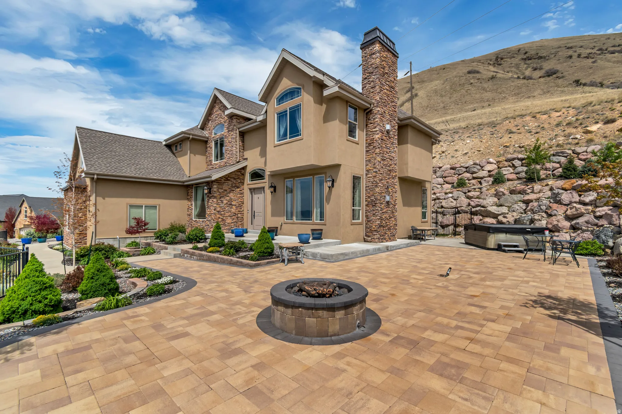 Back of property featuring an outdoor fire pit, stucco siding, a chimney, stone siding, and a patio area