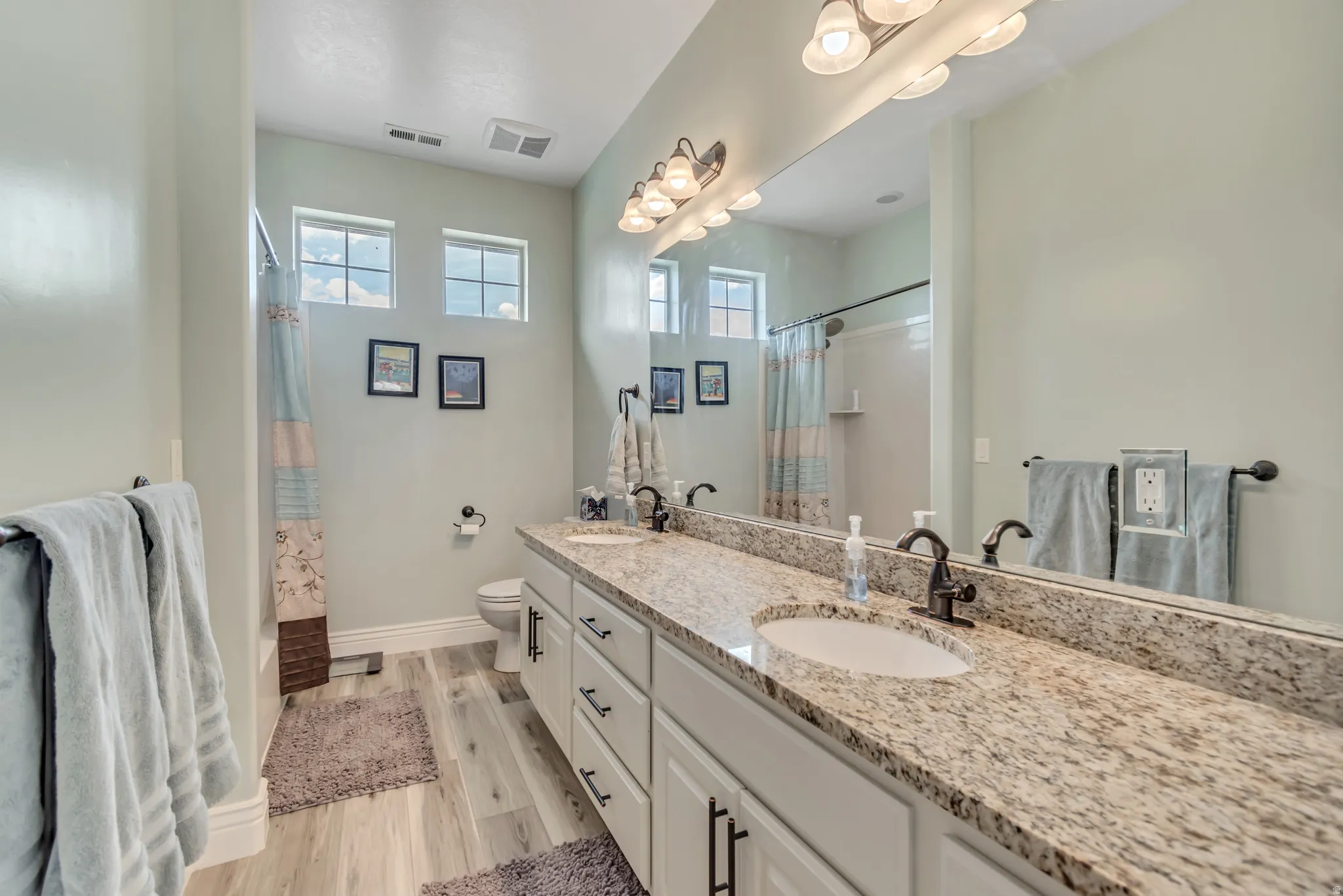 Full bathroom with double vanity and light wood finished floors