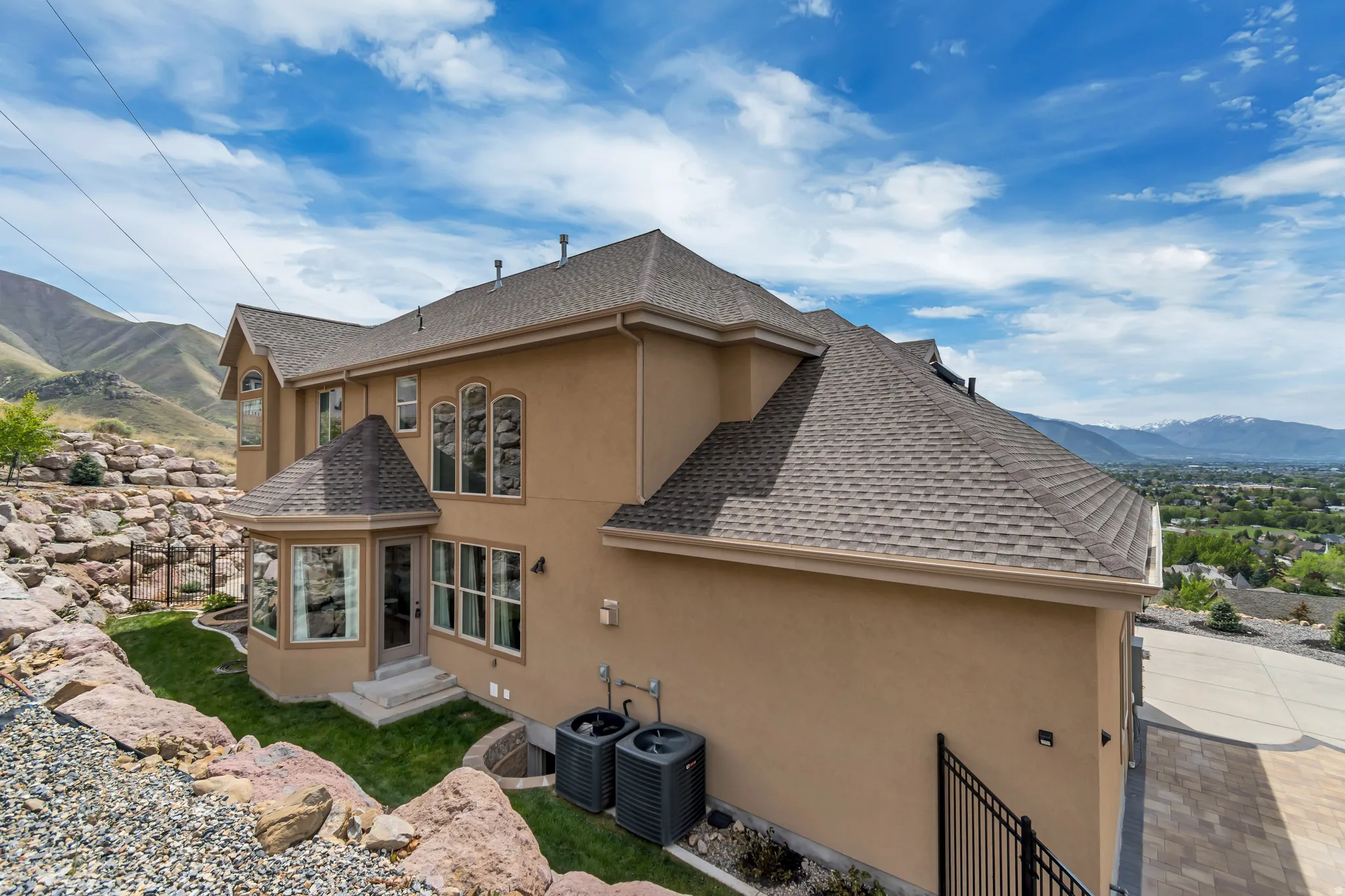 View of side of property featuring a mountain view, a shingled roof, and stucco siding