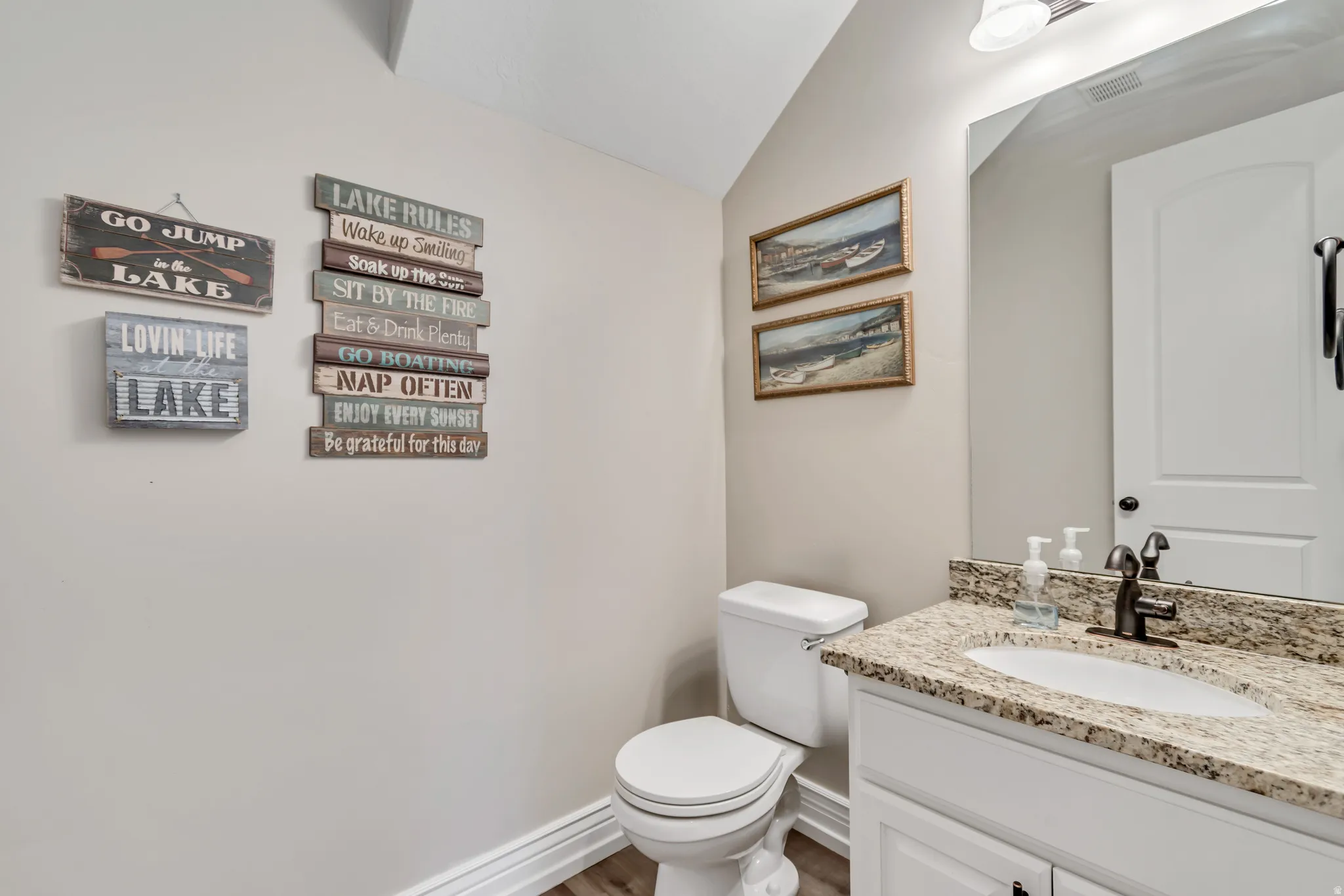 Bathroom featuring vanity, lofted ceiling, and wood finished floors