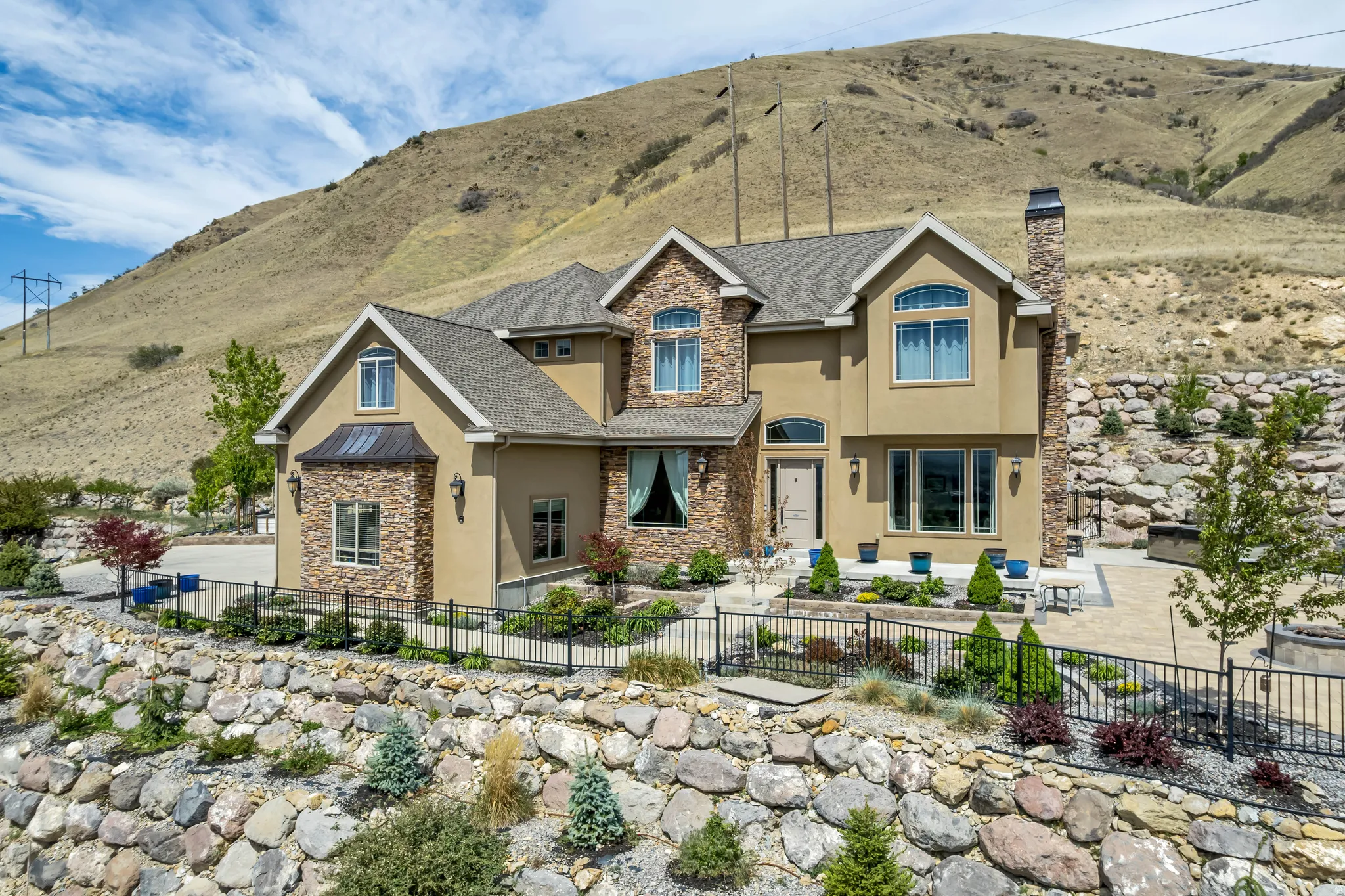 Craftsman-style house featuring stone siding, stucco siding, a fenced front yard, a chimney, and a mountain view