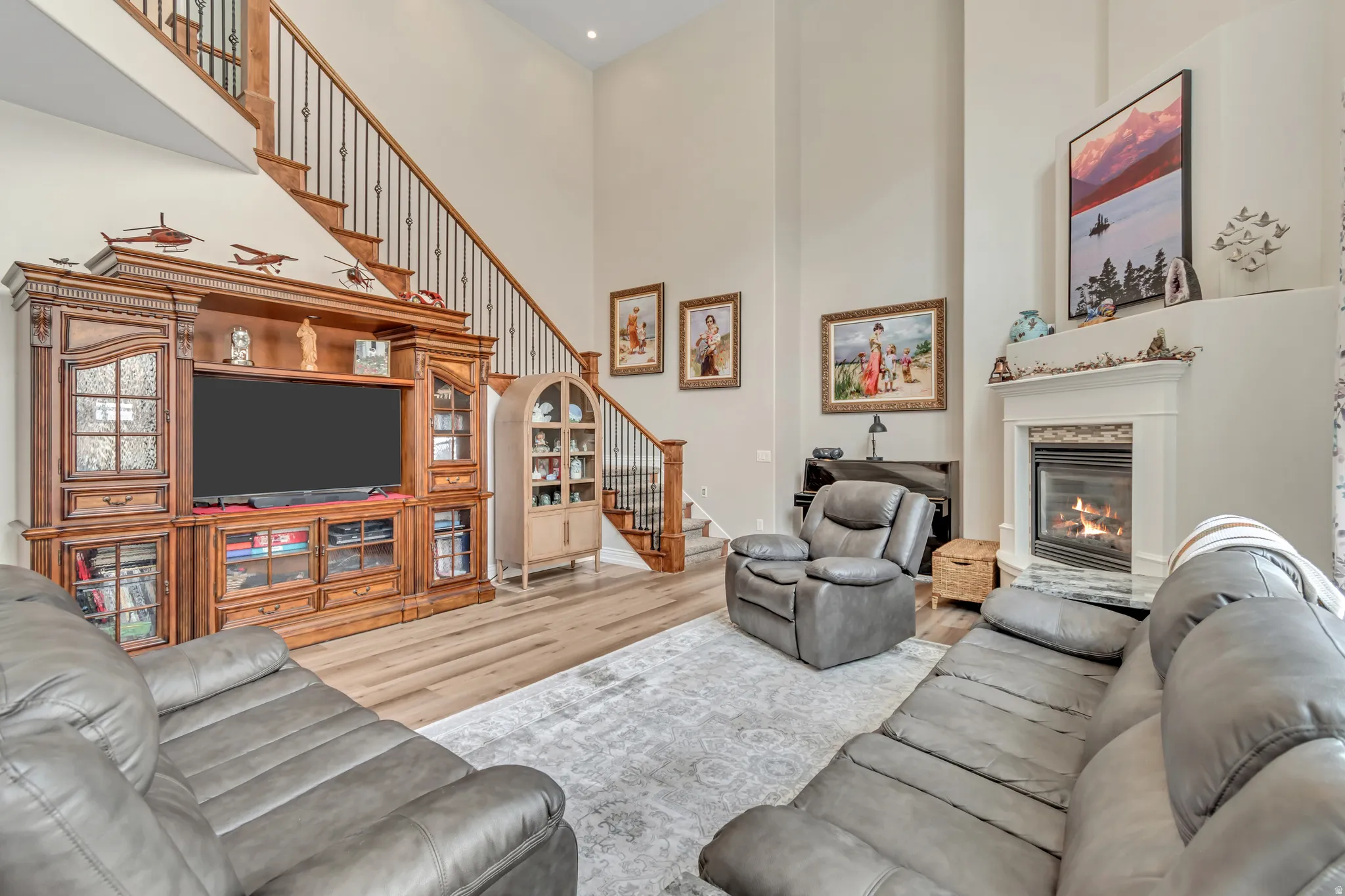 Living area with light wood finished floors, a high ceiling, and a glass covered fireplace