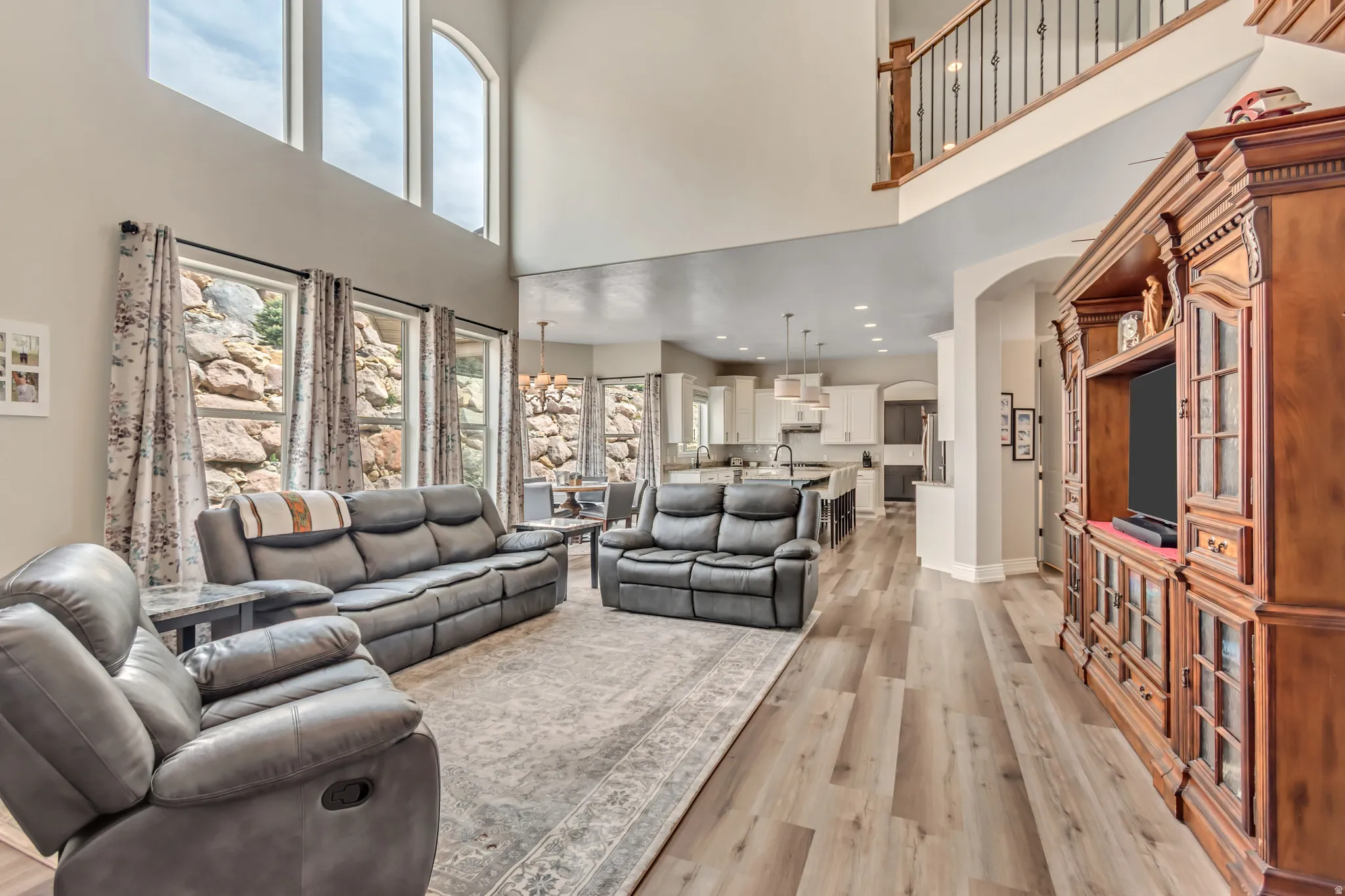 Living room with light wood-style flooring, arched walkways, a high ceiling, and recessed lighting
