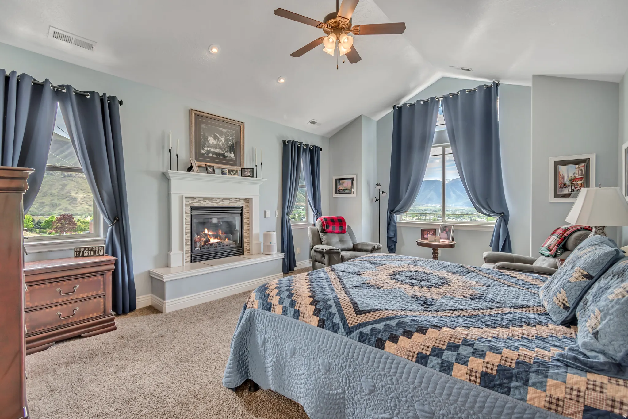 Carpeted bedroom featuring ceiling fan and a glass covered fireplace