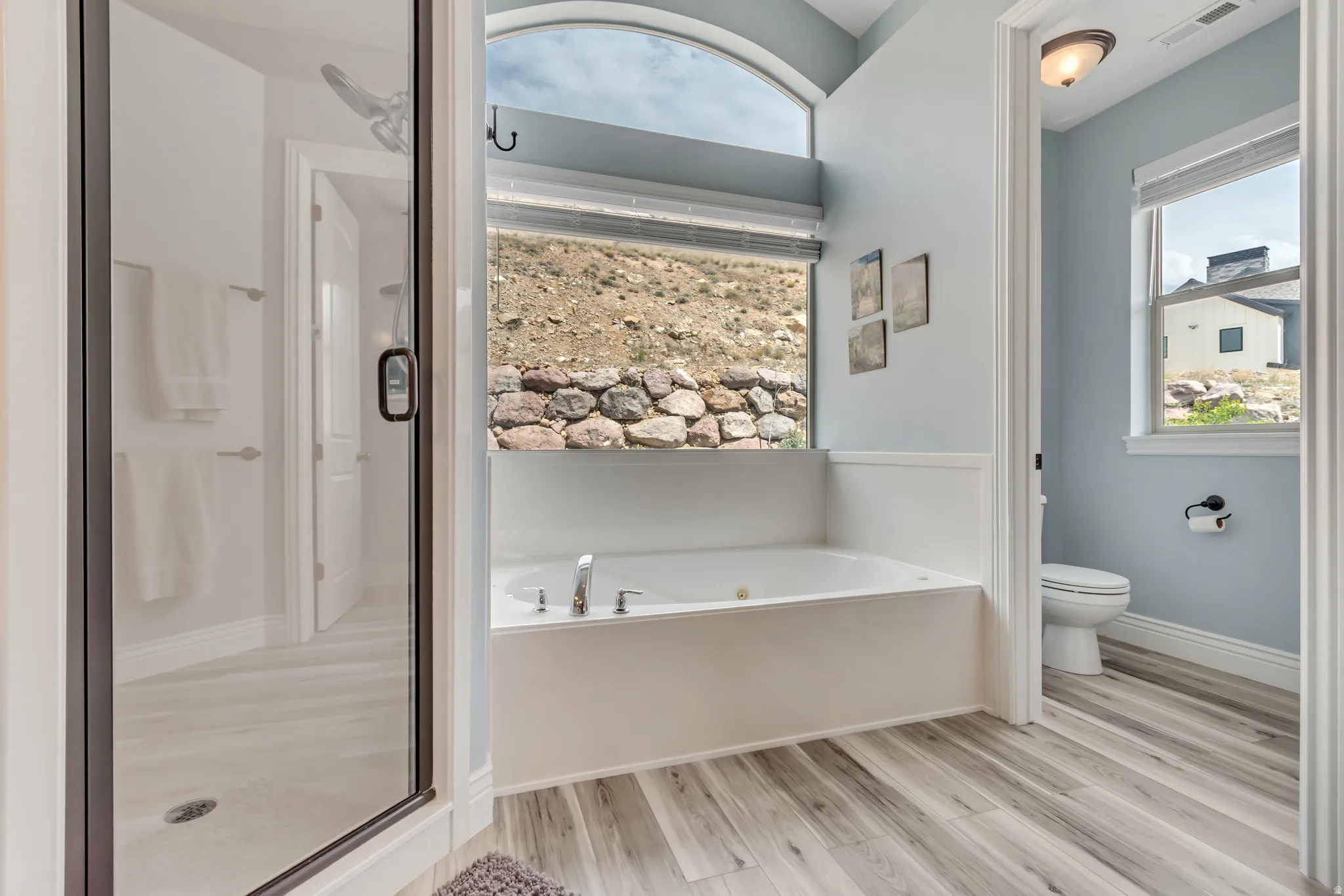 Full bath featuring a stall shower, a whirlpool tub, light wood finished floors, and plenty of natural light