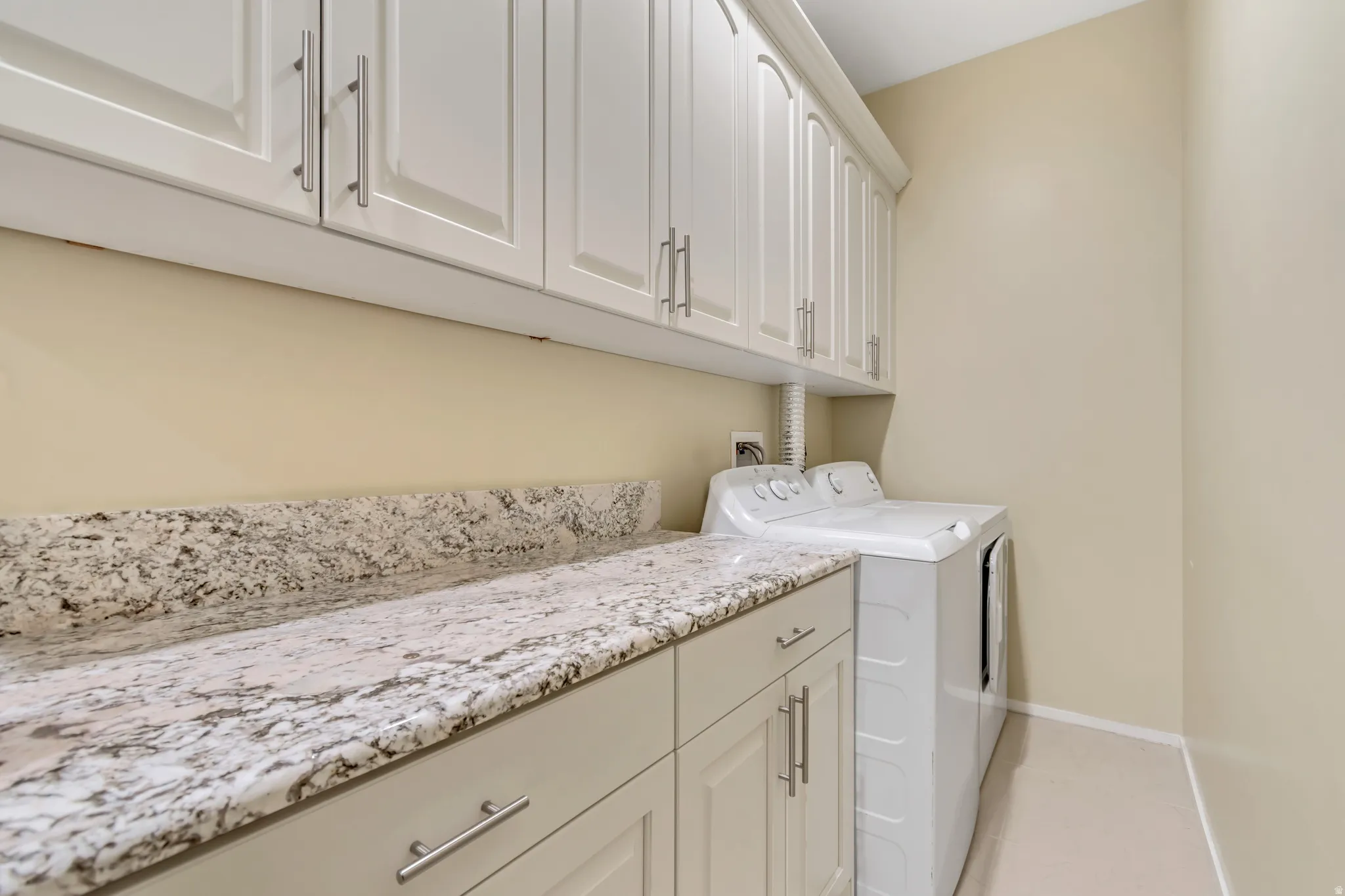 Laundry room with cabinet space, washer and clothes dryer, and light tile patterned floors