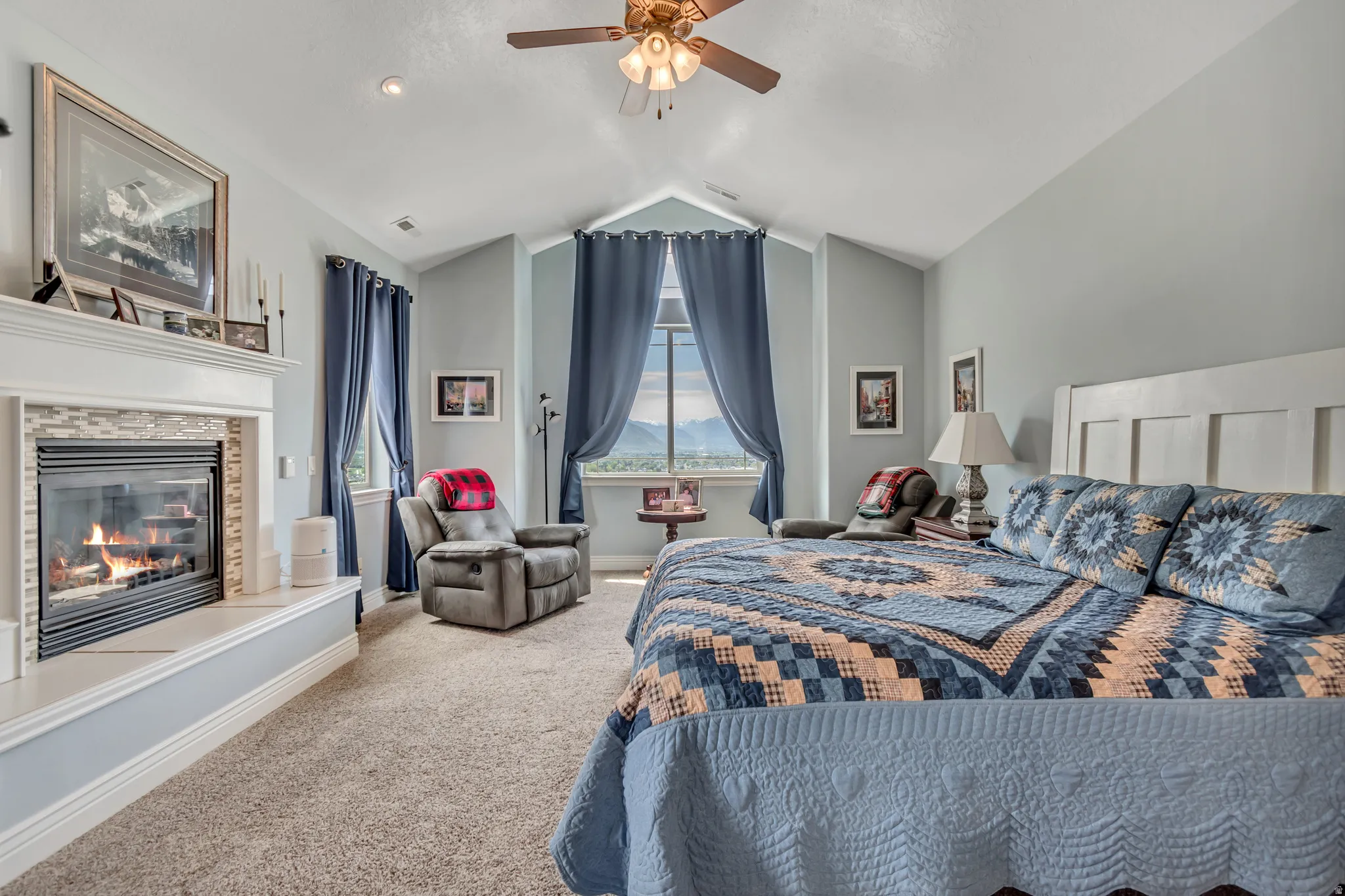 Carpeted bedroom with a tile fireplace and a ceiling fan