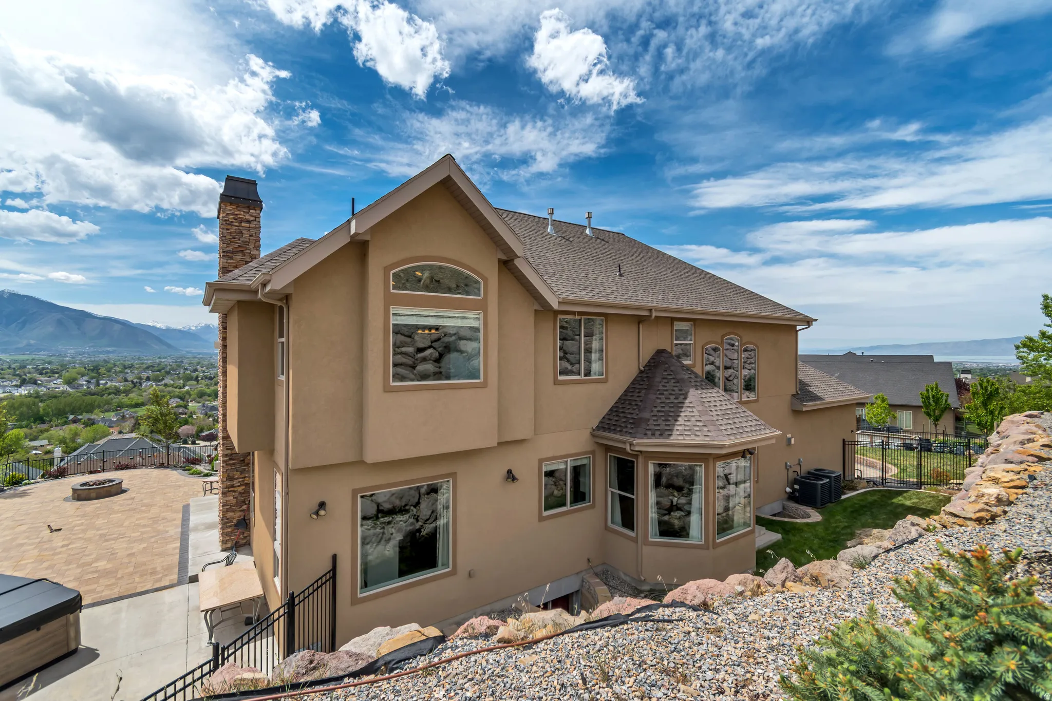 Back of property with stucco siding, a chimney, a mountain view, and roof with shingles