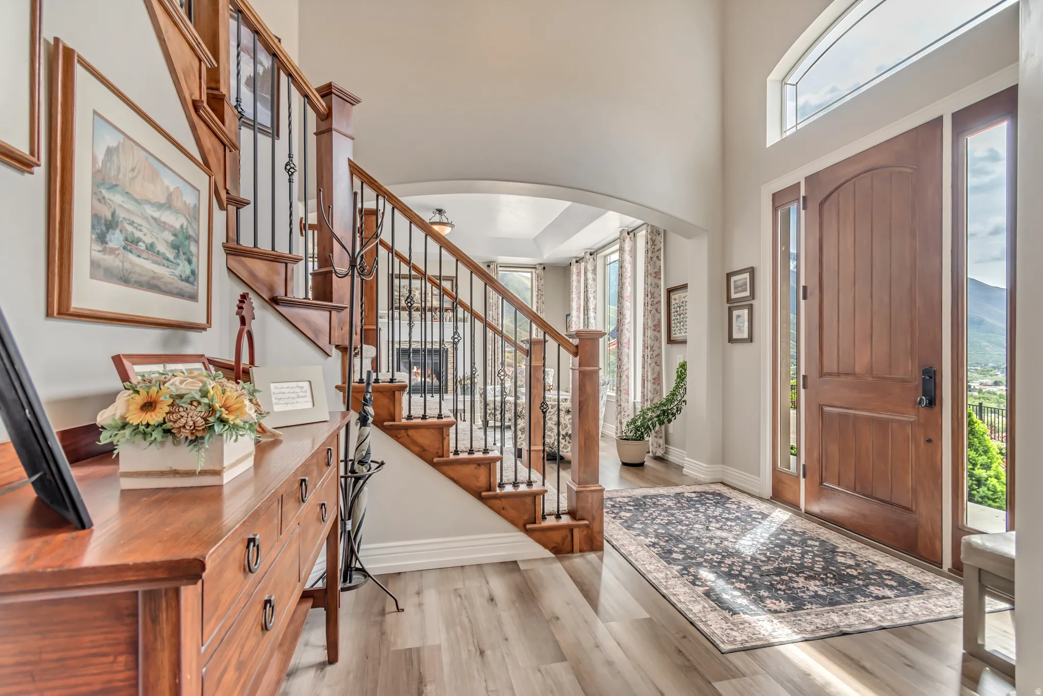 Foyer entrance with light wood-type flooring, arched walkways, and a high ceiling
