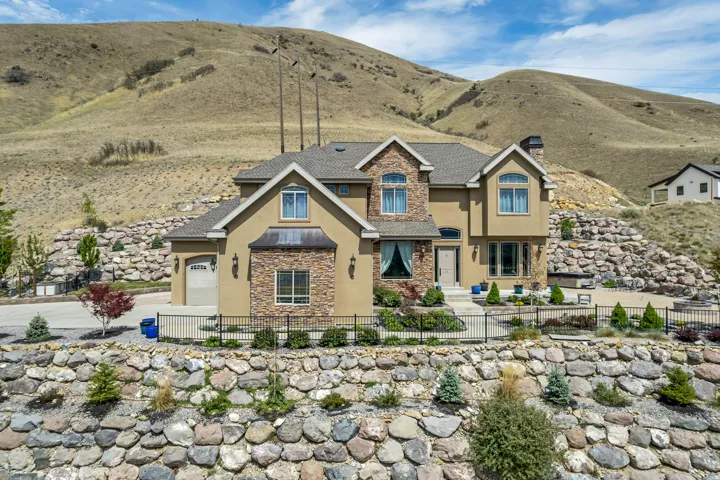 Craftsman-style house featuring stucco siding, stone siding, a fenced front yard, and a mountain view