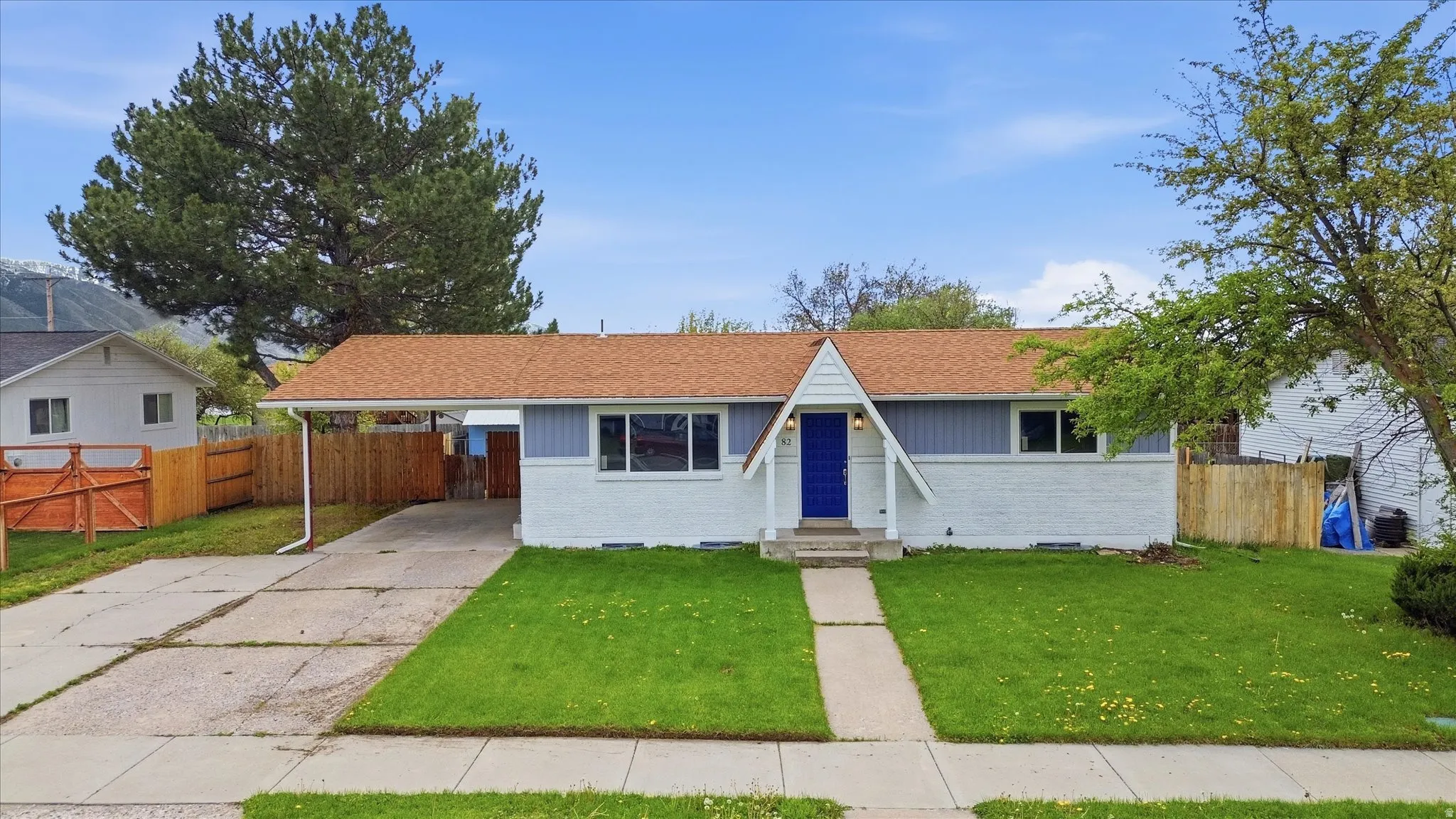 View of front of house featuring brick siding, a shingled roof, a carport, and driveway