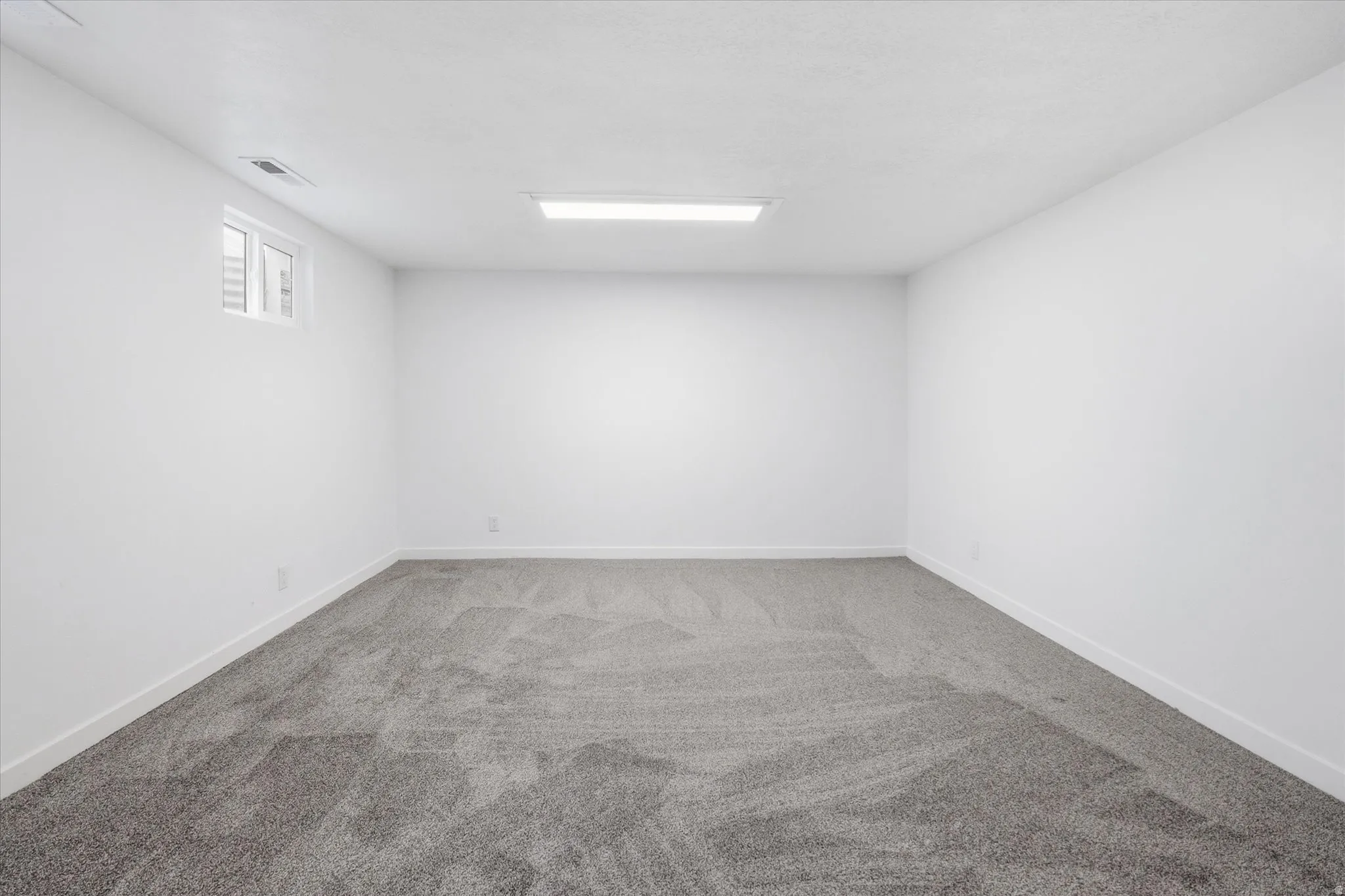 Spare room featuring light colored carpet and baseboards