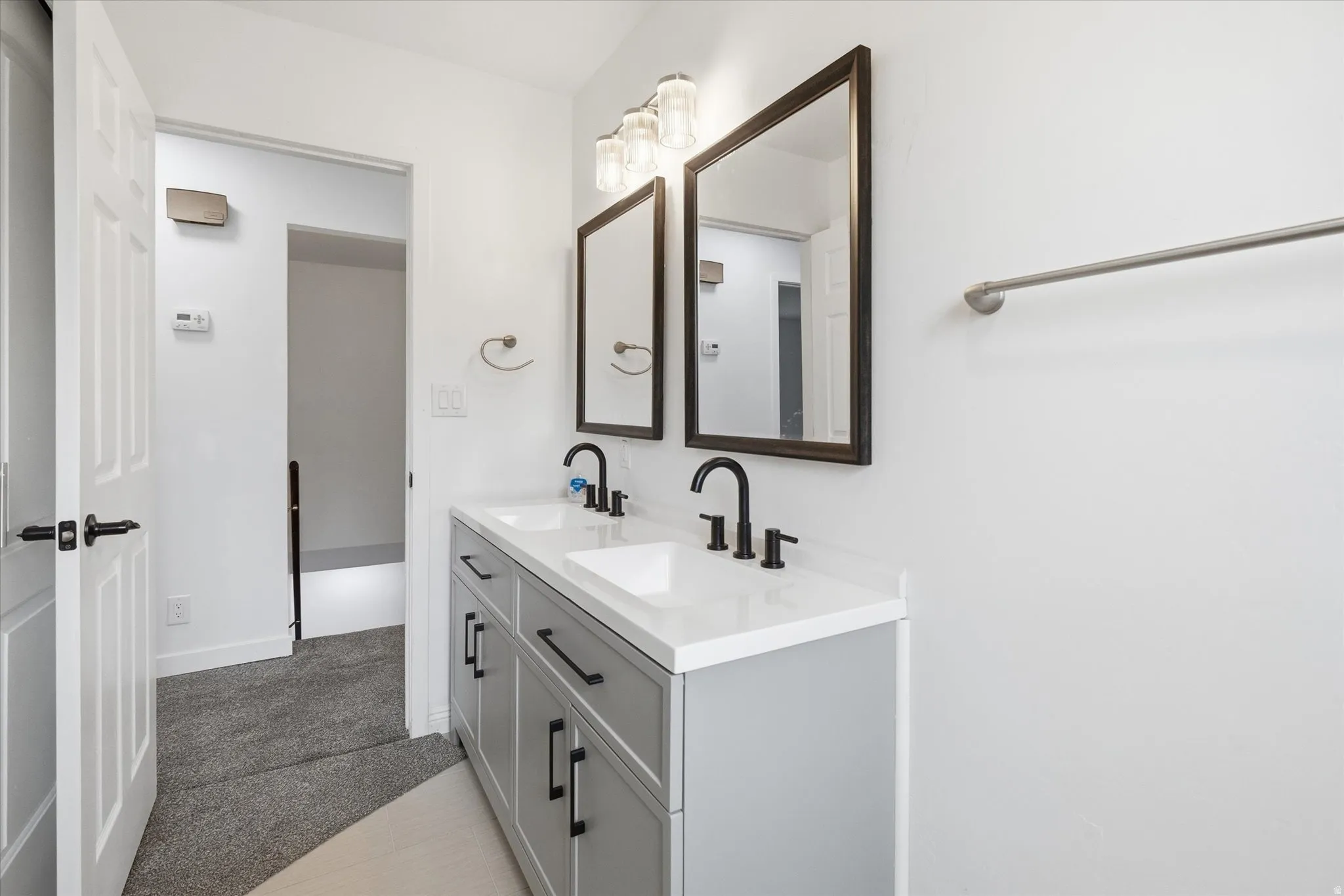 Full bath with double vanity and dark colored carpet