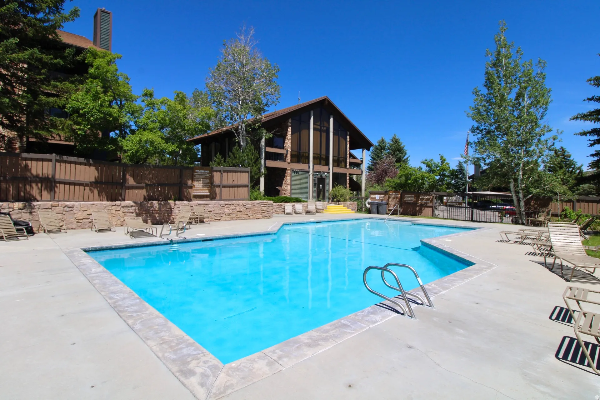 Outdoor swimming pool with concrete decking and stone-capped retaining walls