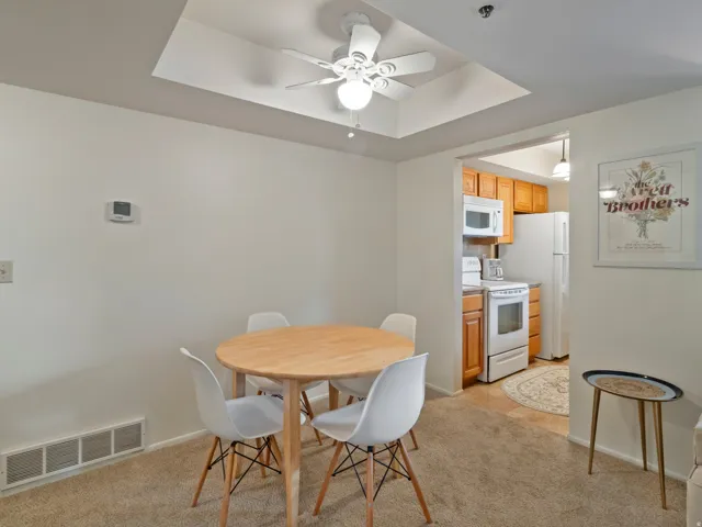 Dining area featuring a ceiling fan, a raised ceiling, and light colored carpet