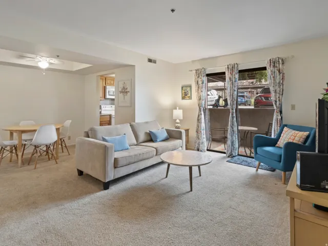 Living area with ceiling fan and light colored carpet
