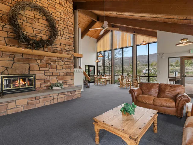 Carpeted living area featuring a mountain view, a stone fireplace, ceiling fan, and french doors