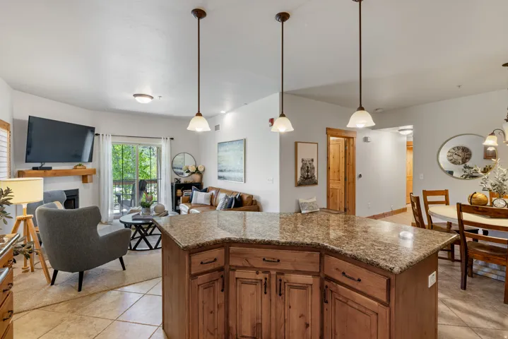 Kitchen featuring decorative light fixtures, open floor plan, wood finish cabinetry, a kitchen island, and a fireplace