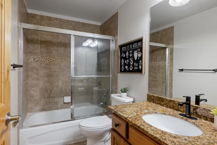 Bathroom featuring vanity and bath / shower combo with glass door