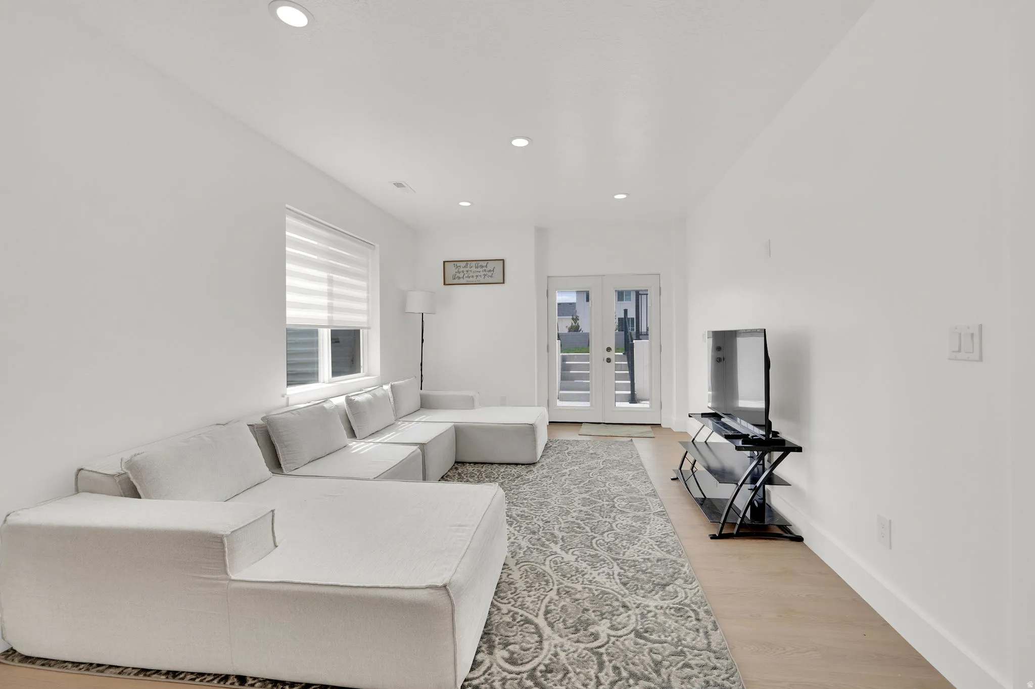 Living area with french doors, light wood-style floors, and recessed lighting
