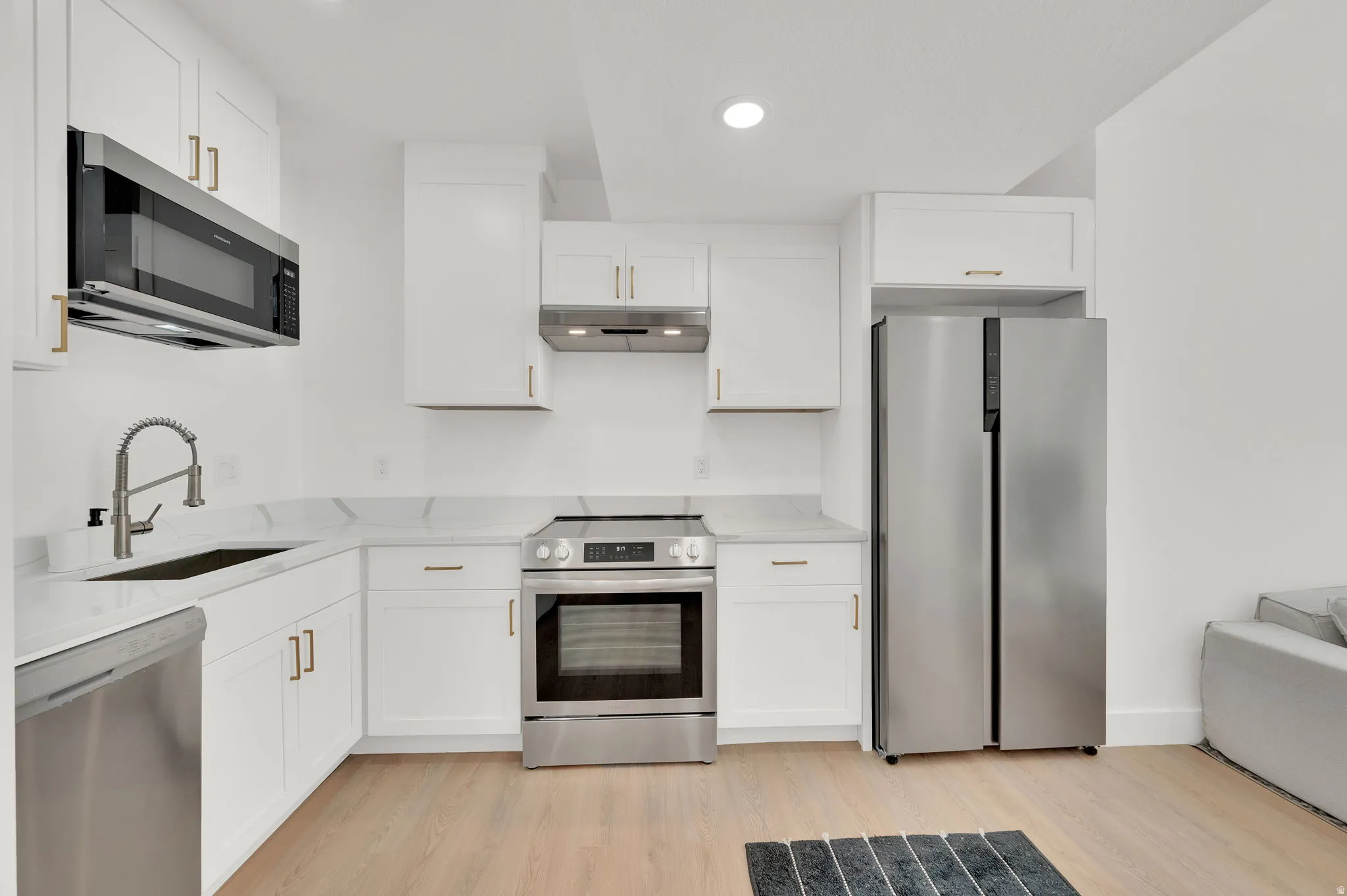 Kitchen featuring stainless steel appliances, light wood-type flooring, light stone countertops, and recessed lighting